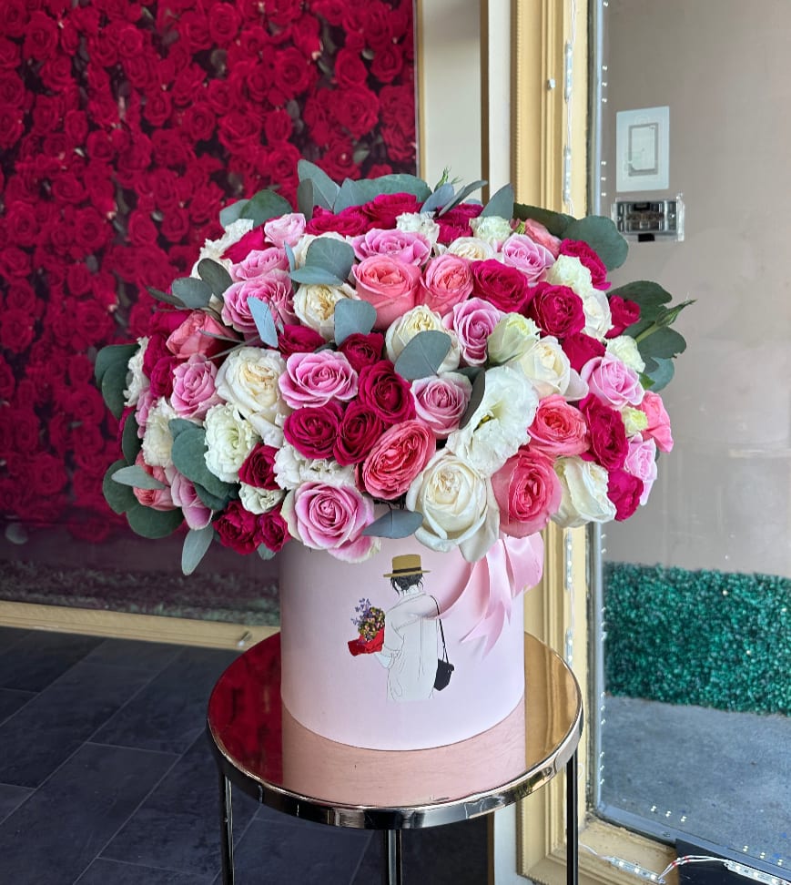 Large pink and white rose arrangement in a round hat box