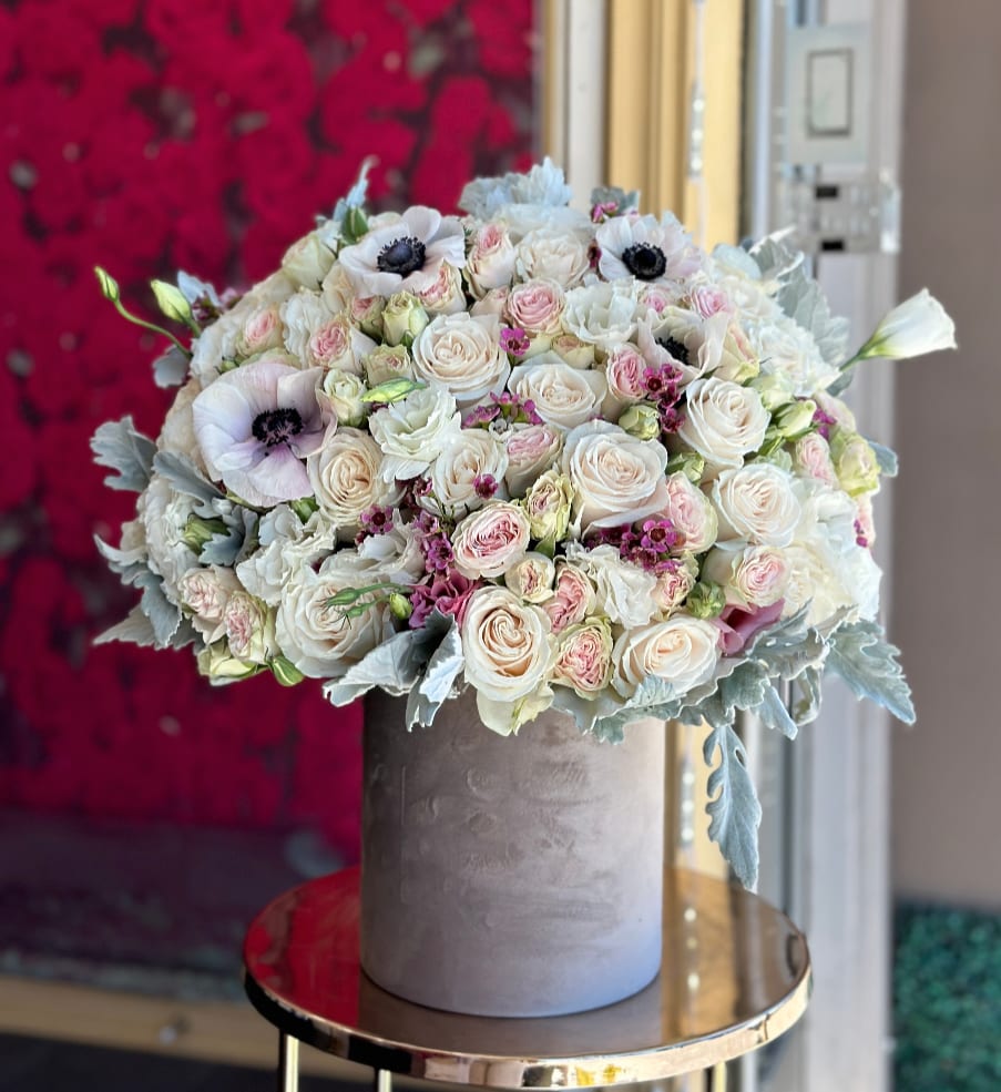Round bouquet of white and blush roses in a gray hatbox