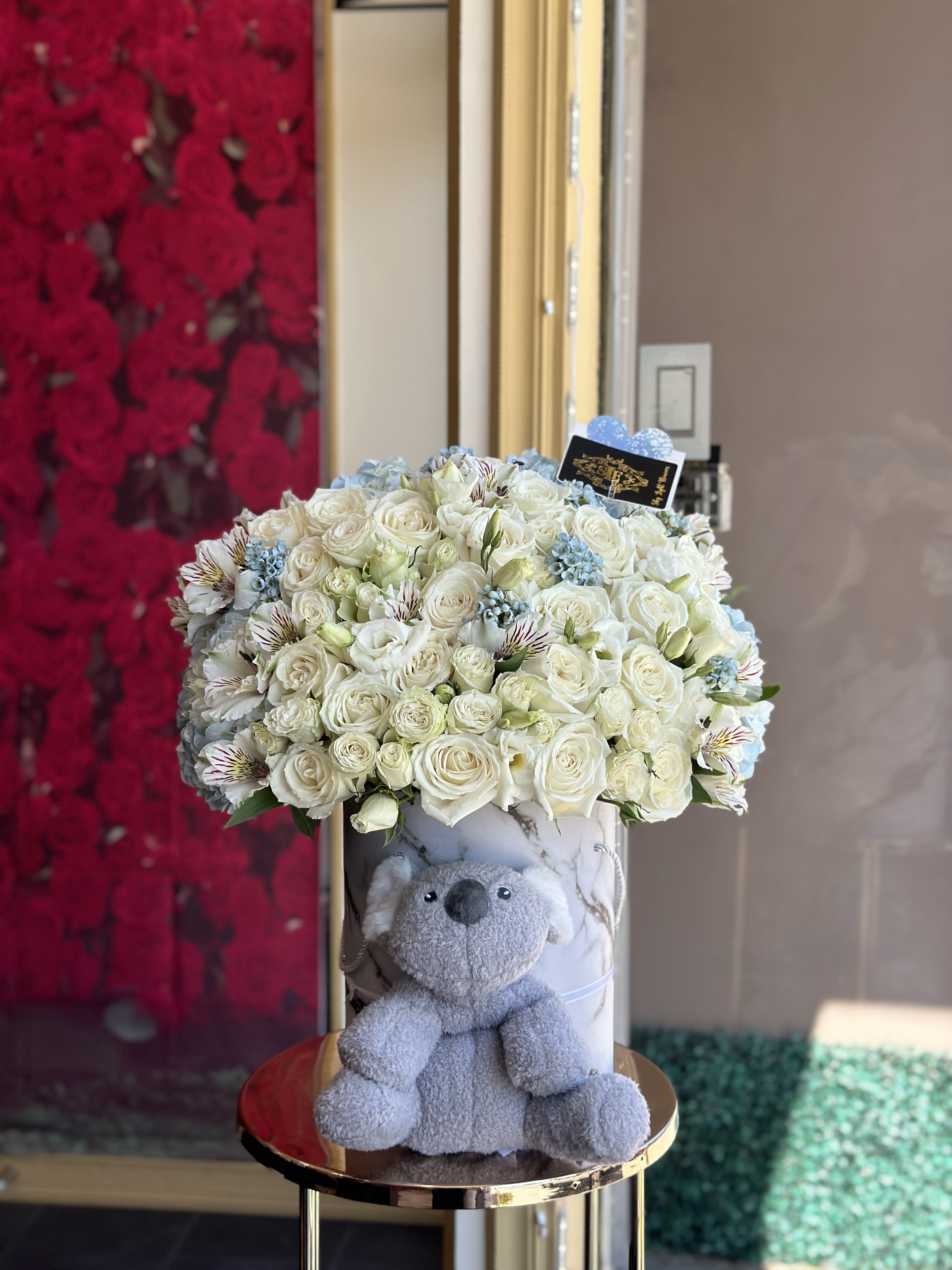 White rose bouquet in a marble box with a gray teddy bear