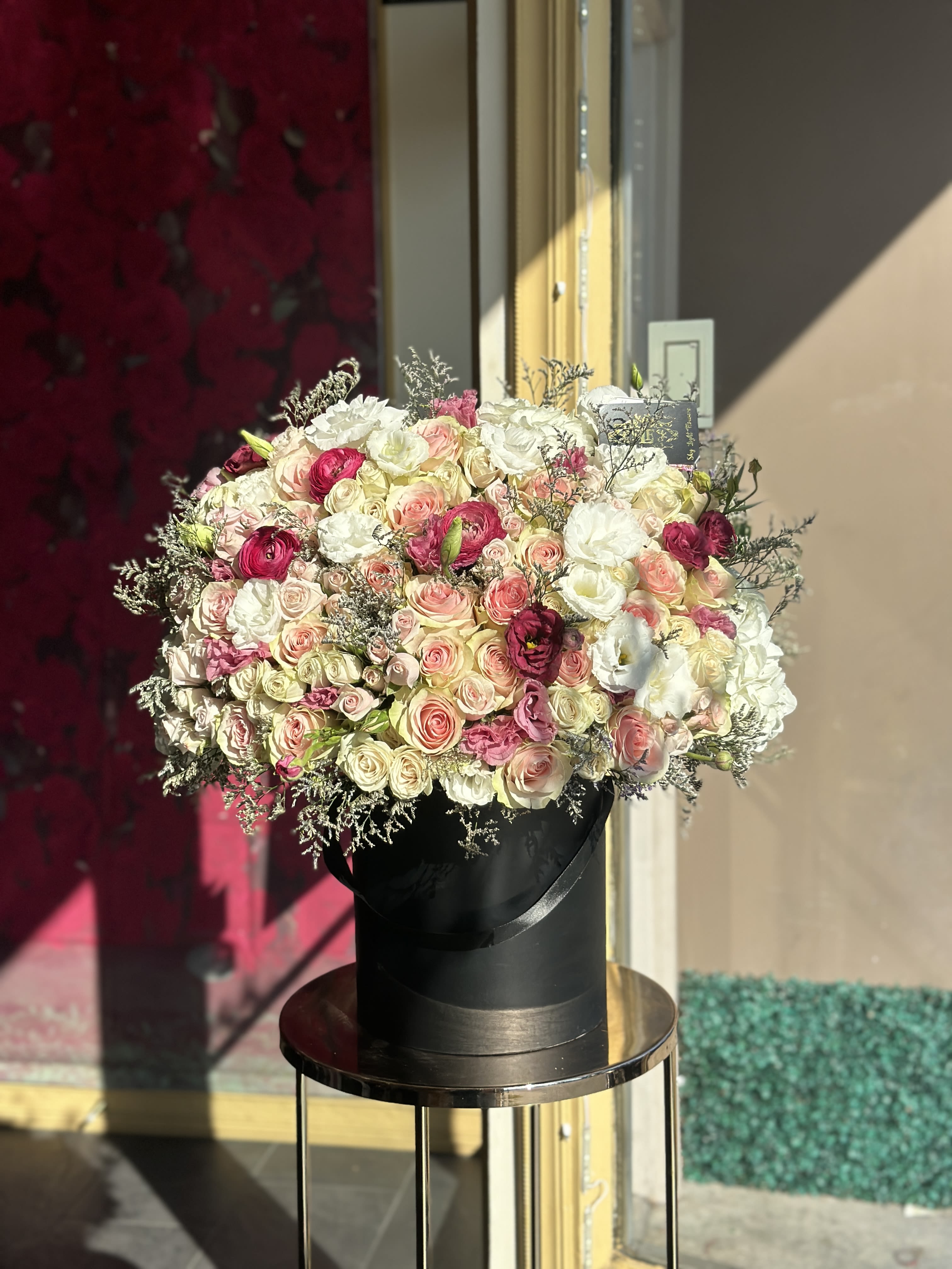 Large bouquet of pink, white, and cream roses in a black hat box