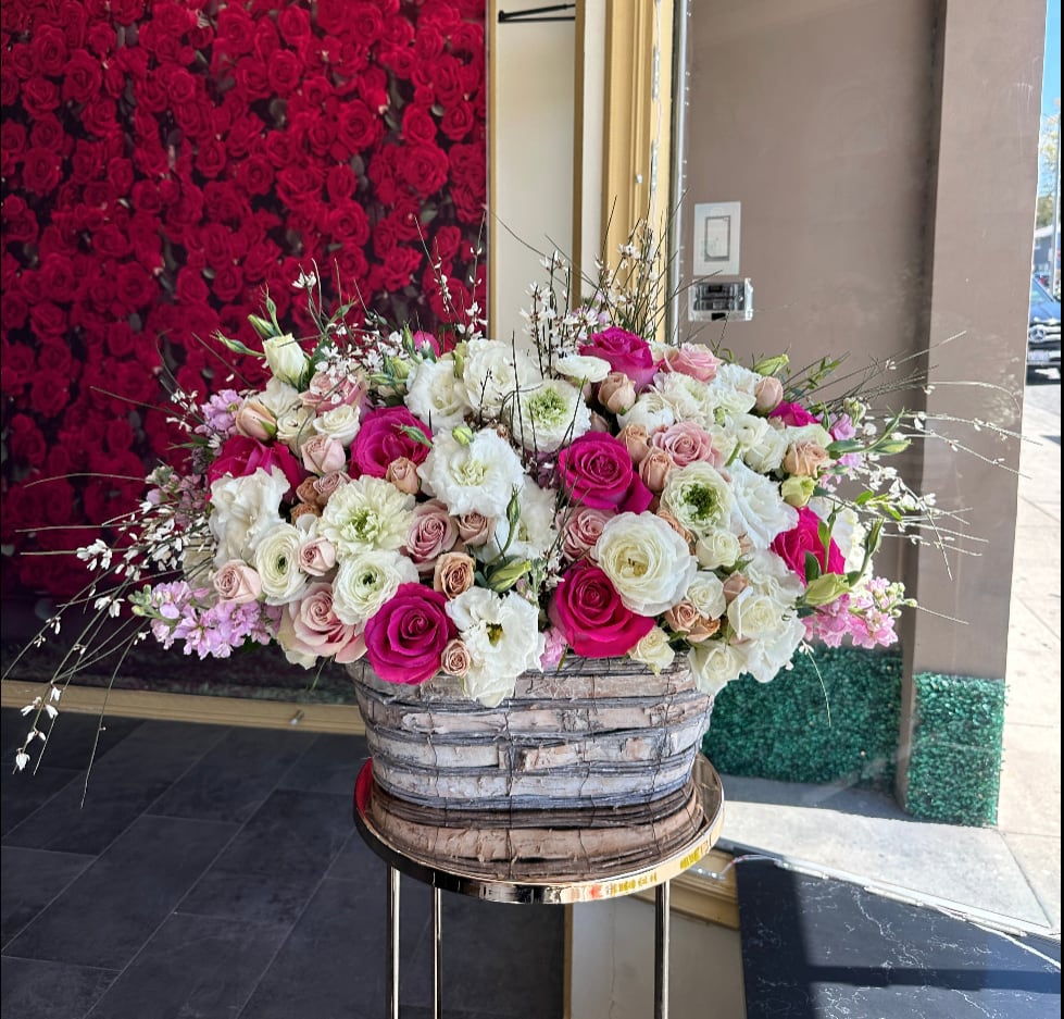 Large mixed rose arrangement in a woven basket on a stand