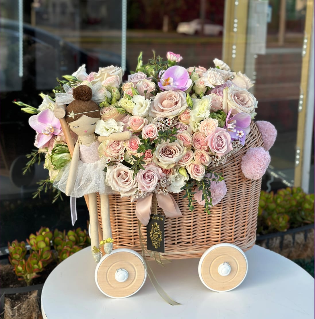 Pastel rose bouquet in a wicker basket with a doll decoration