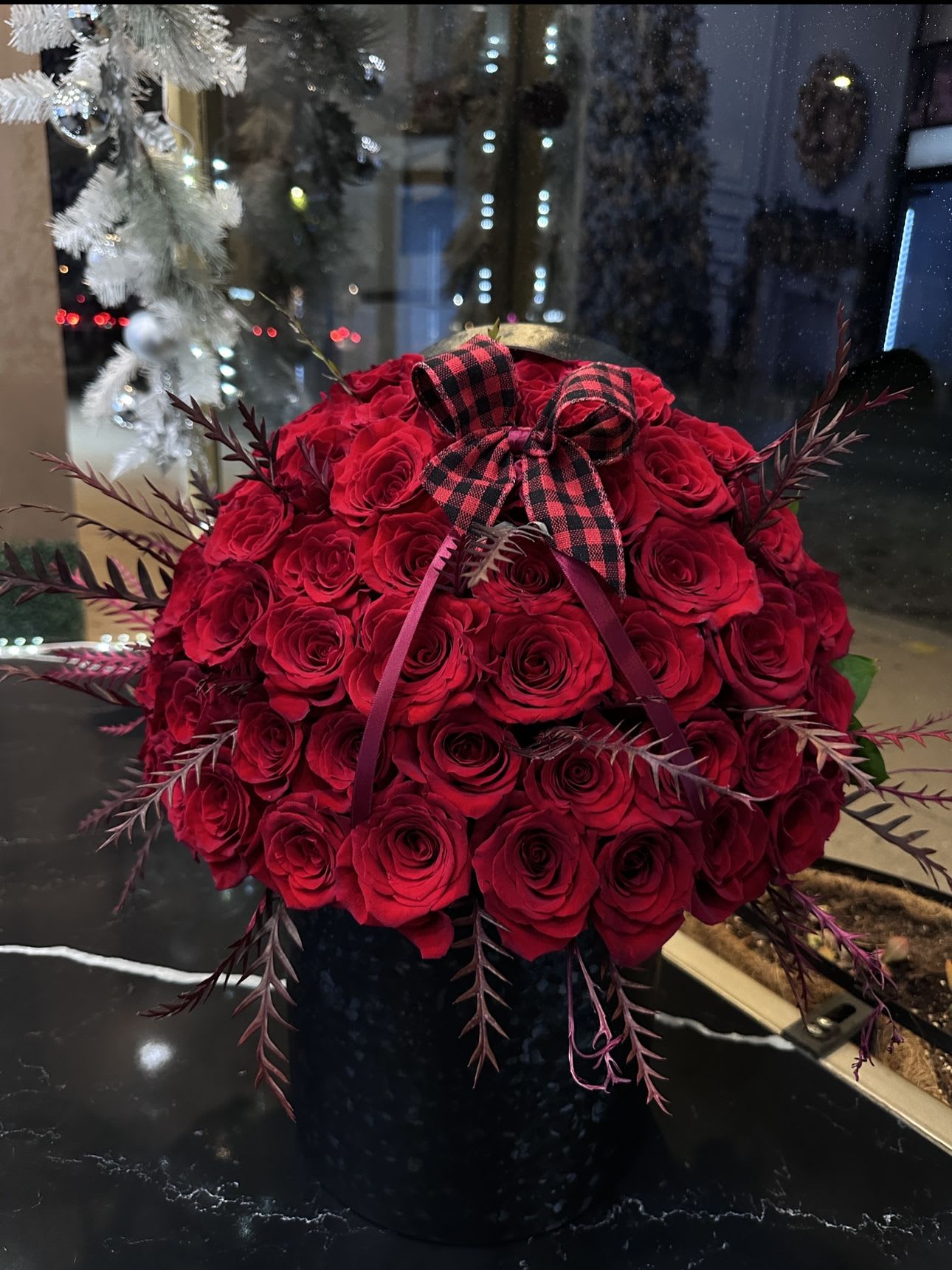 Red rose bouquet with a plaid bow in a black vase