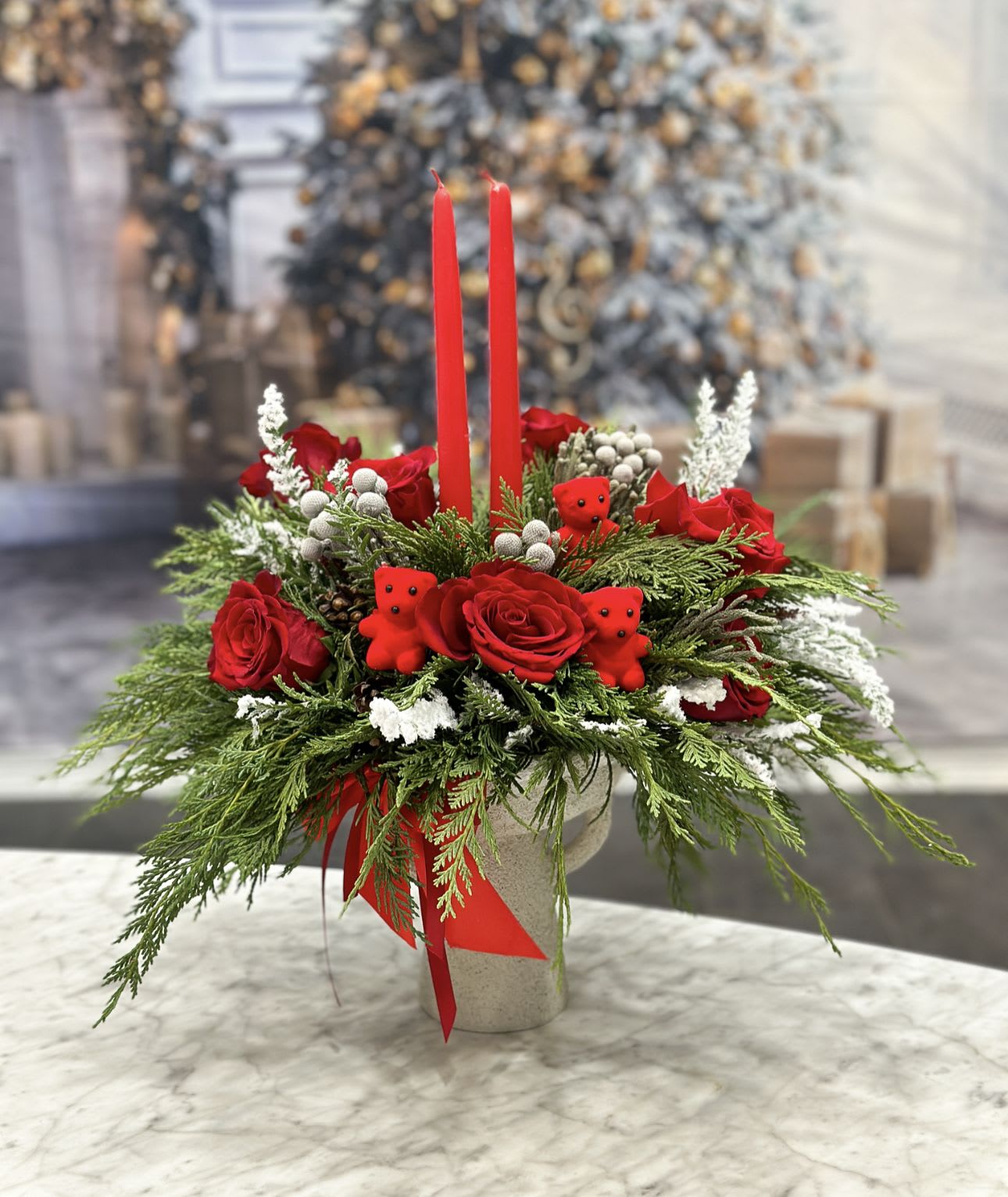 Red roses and holiday greenery in a vase with two red candles