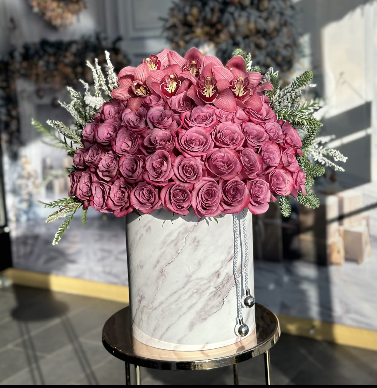 Pink roses and orchids arranged in a marble-patterned hat box