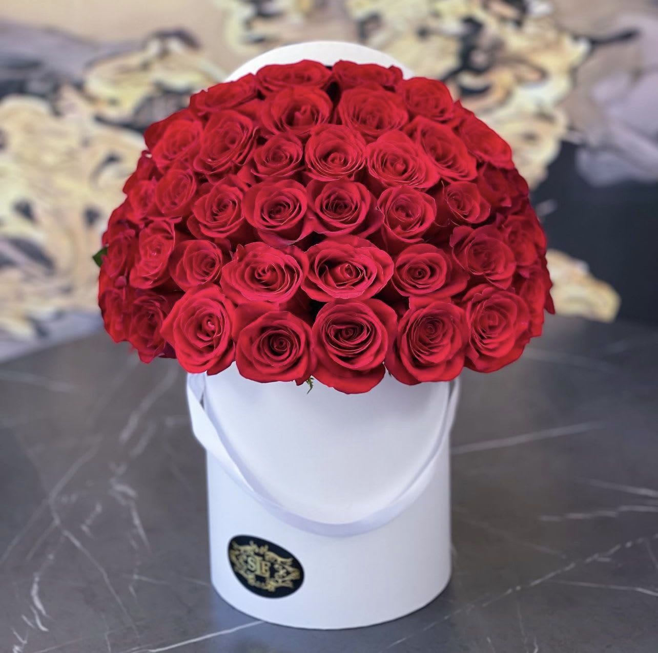 Round bouquet of red roses in a white hat box