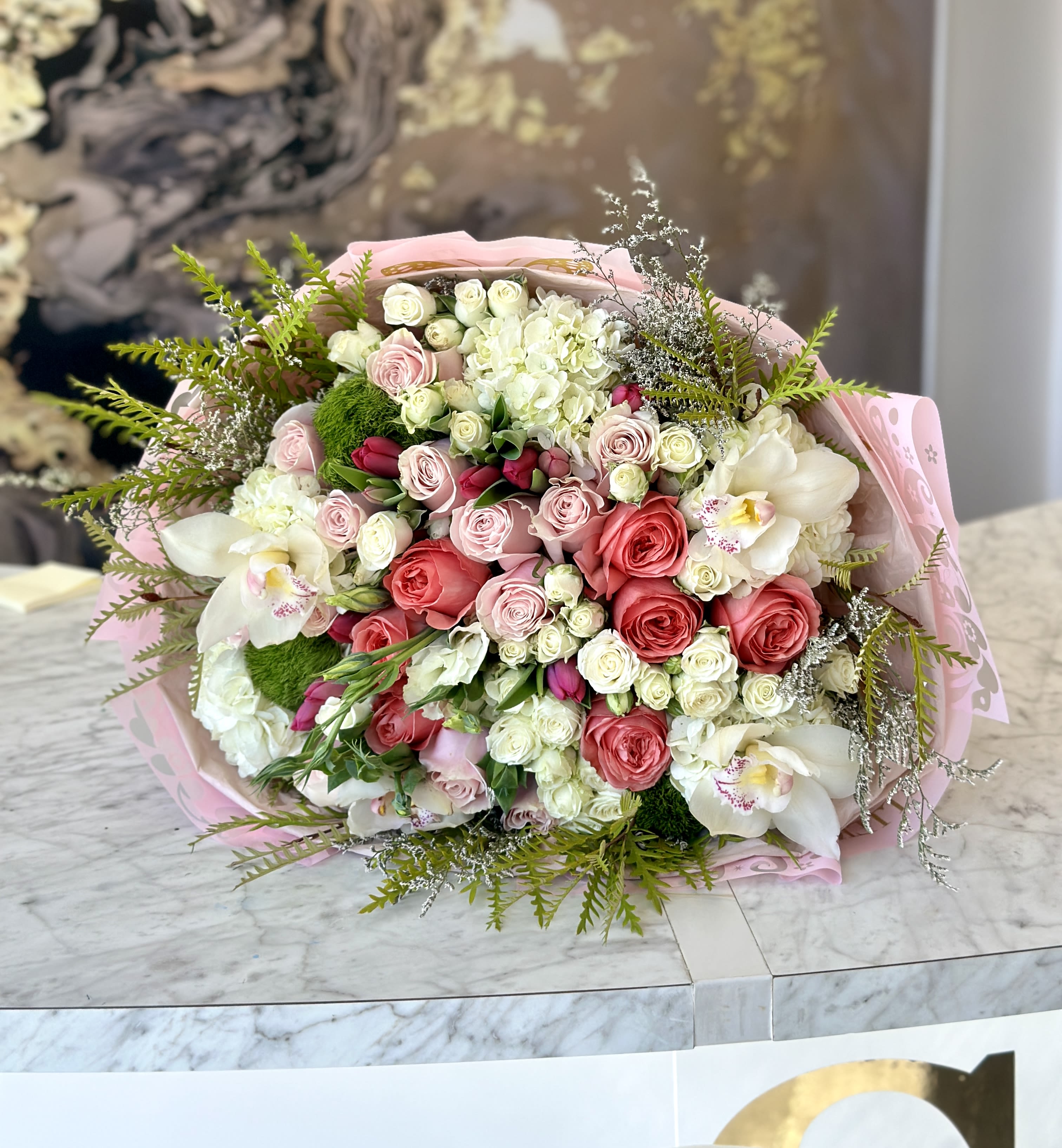 Bouquet of pink and white roses with white orchids wrapped in pink paper