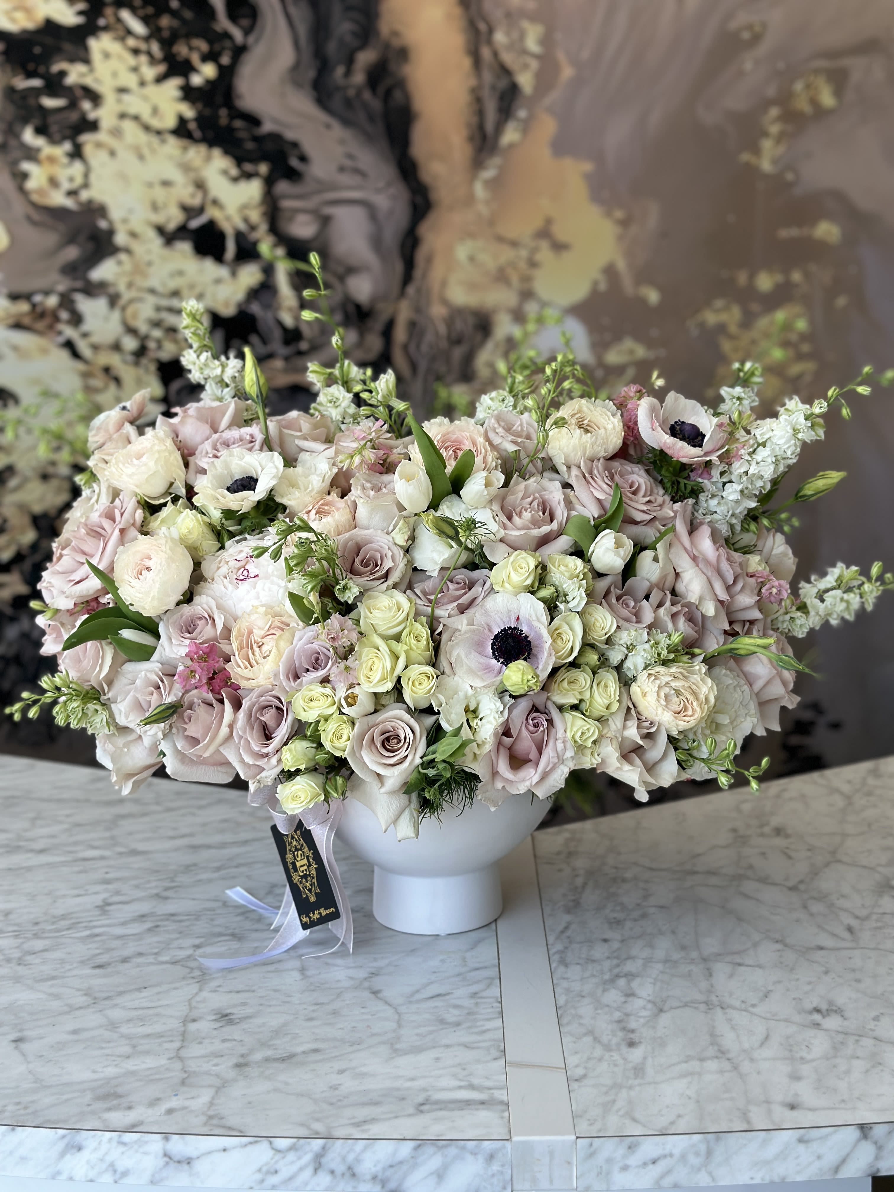 Large pastel bouquet of roses and anemones in a white vase
