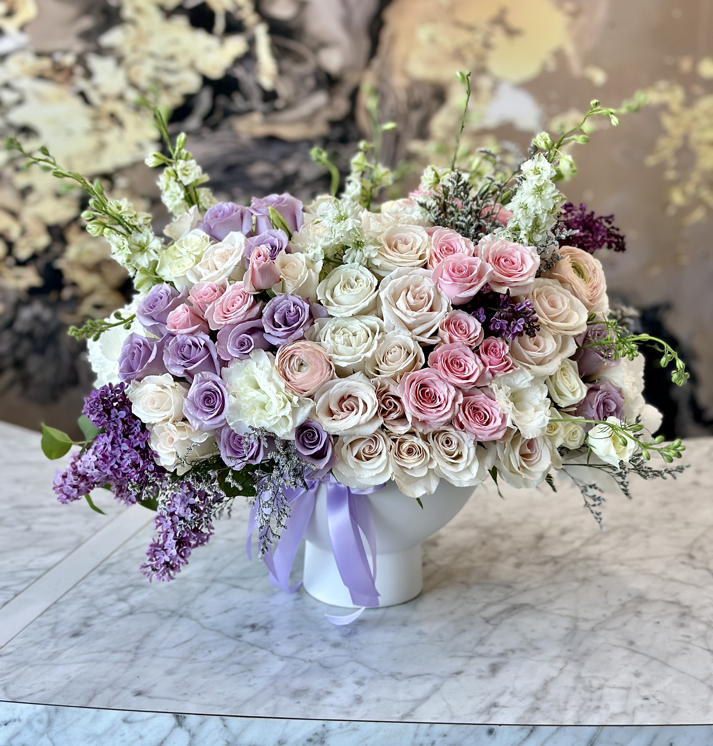 Large bouquet of pink, white, and lavender roses in a white vase