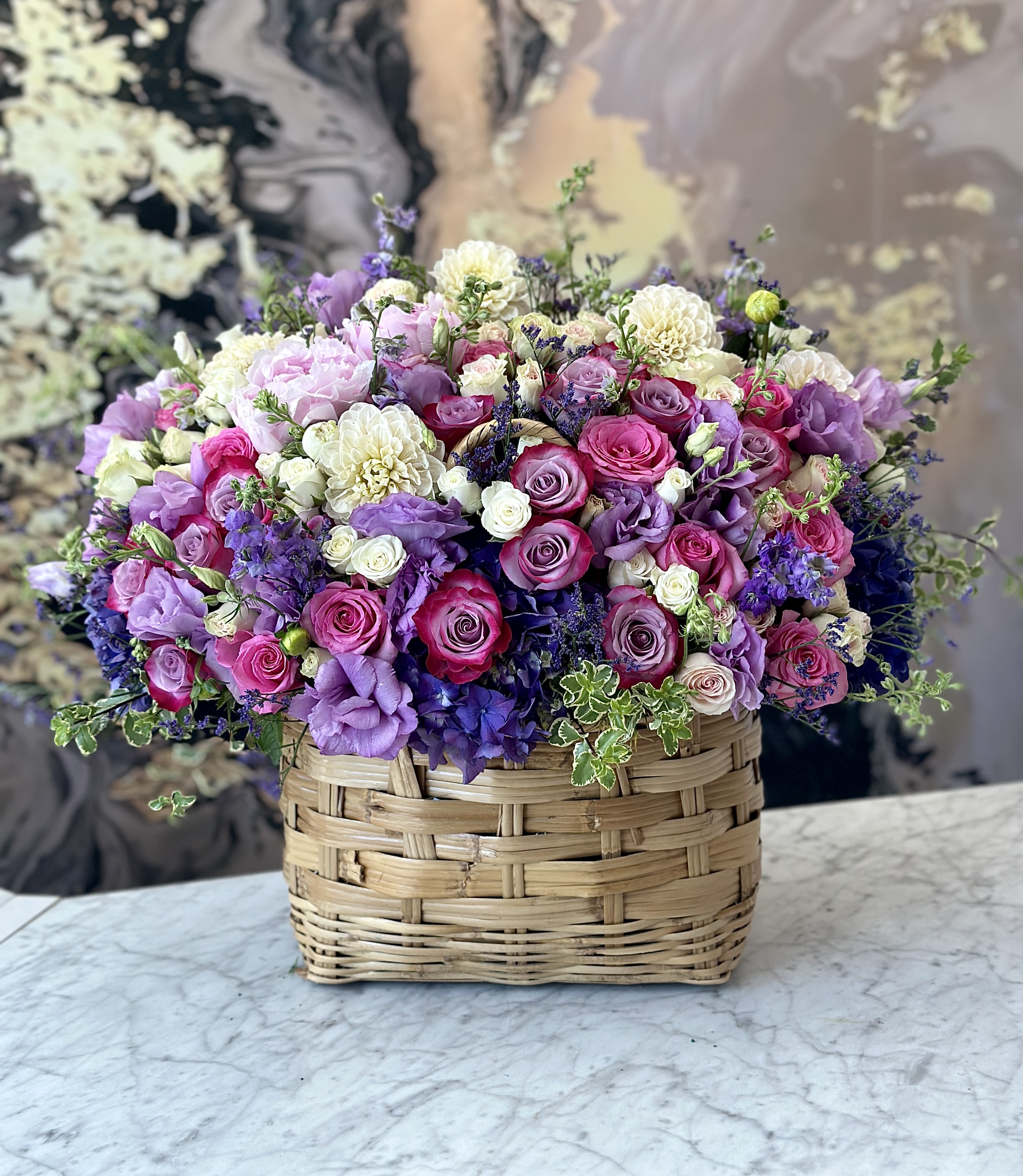 Mixed pink, purple, and white flowers in a woven basket