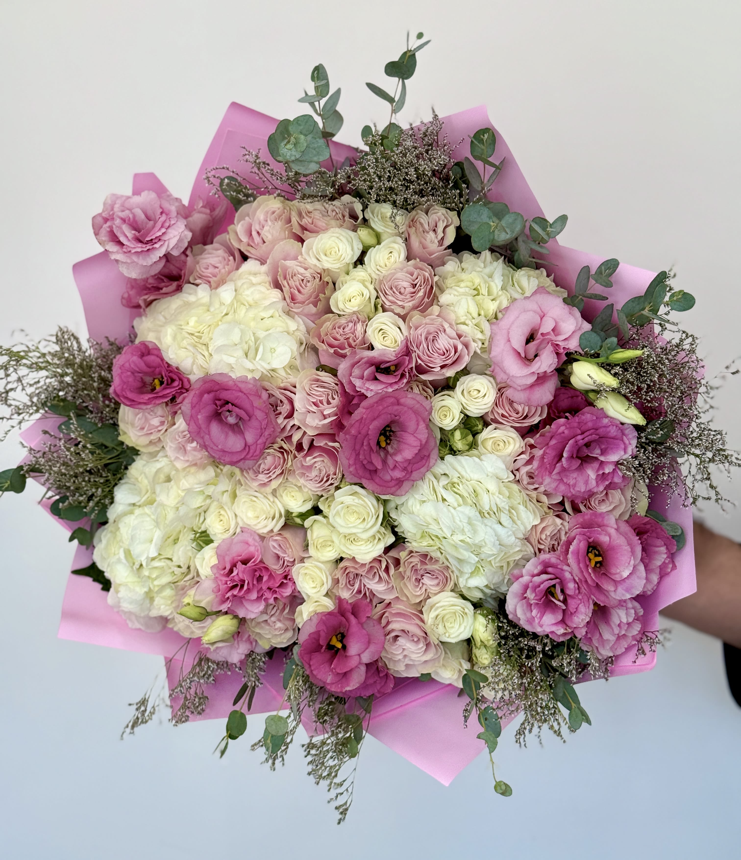 Pink and white bouquet of roses and lisianthus wrapped in pink paper