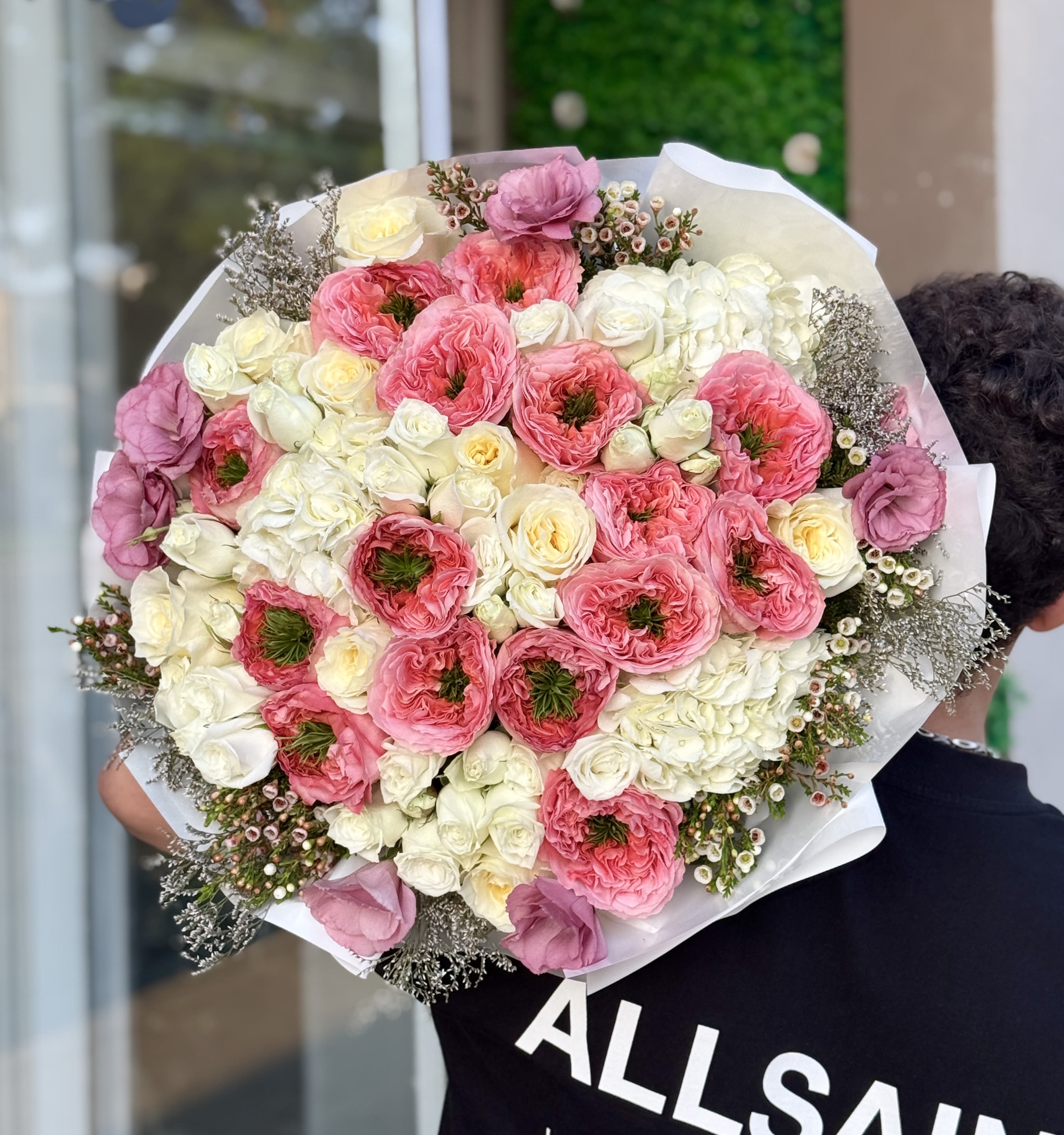 Large bouquet of pink and white flowers wrapped in white paper