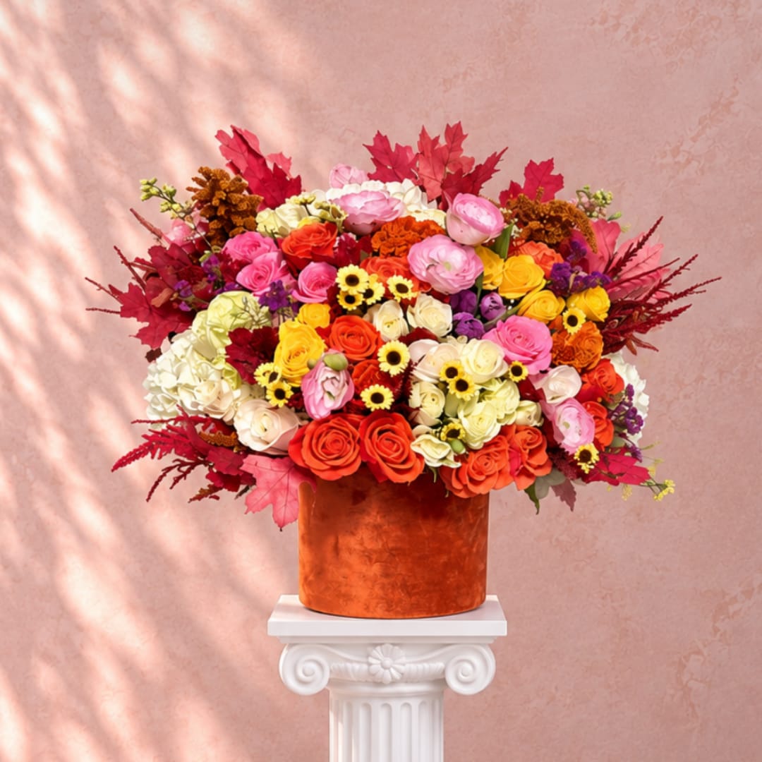 Large mixed bouquet in an orange vase on a white pedestal