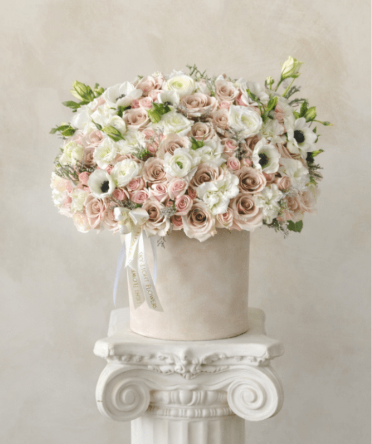 Large pastel rose arrangement in a round box on a pedestal