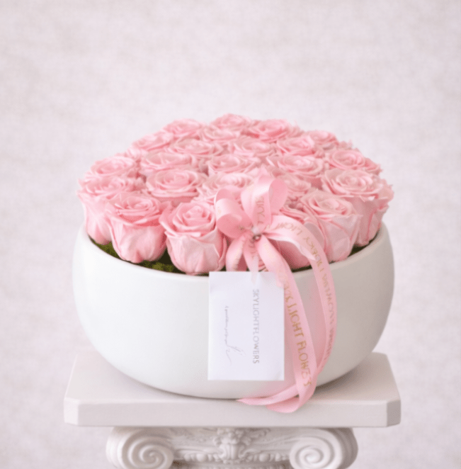 Round box of pale pink roses tied with a pink ribbon