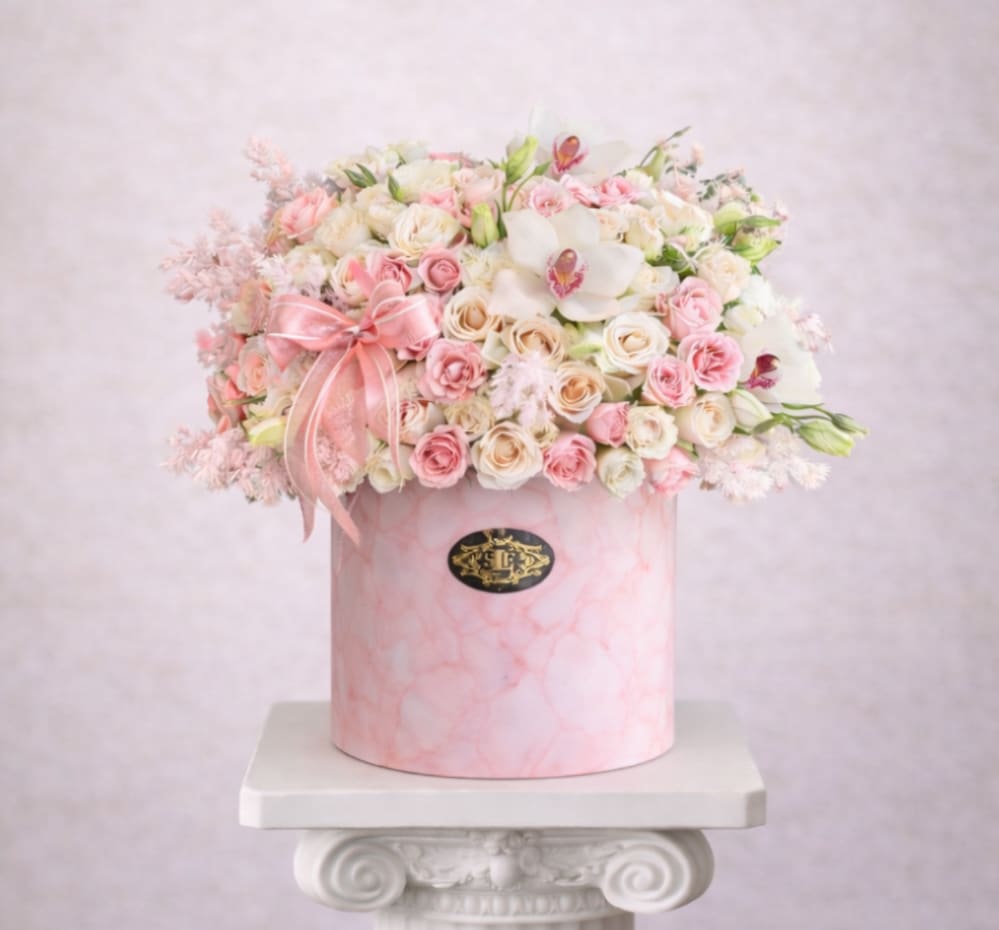 Pink and white rose arrangement in a round pink box with a ribbon