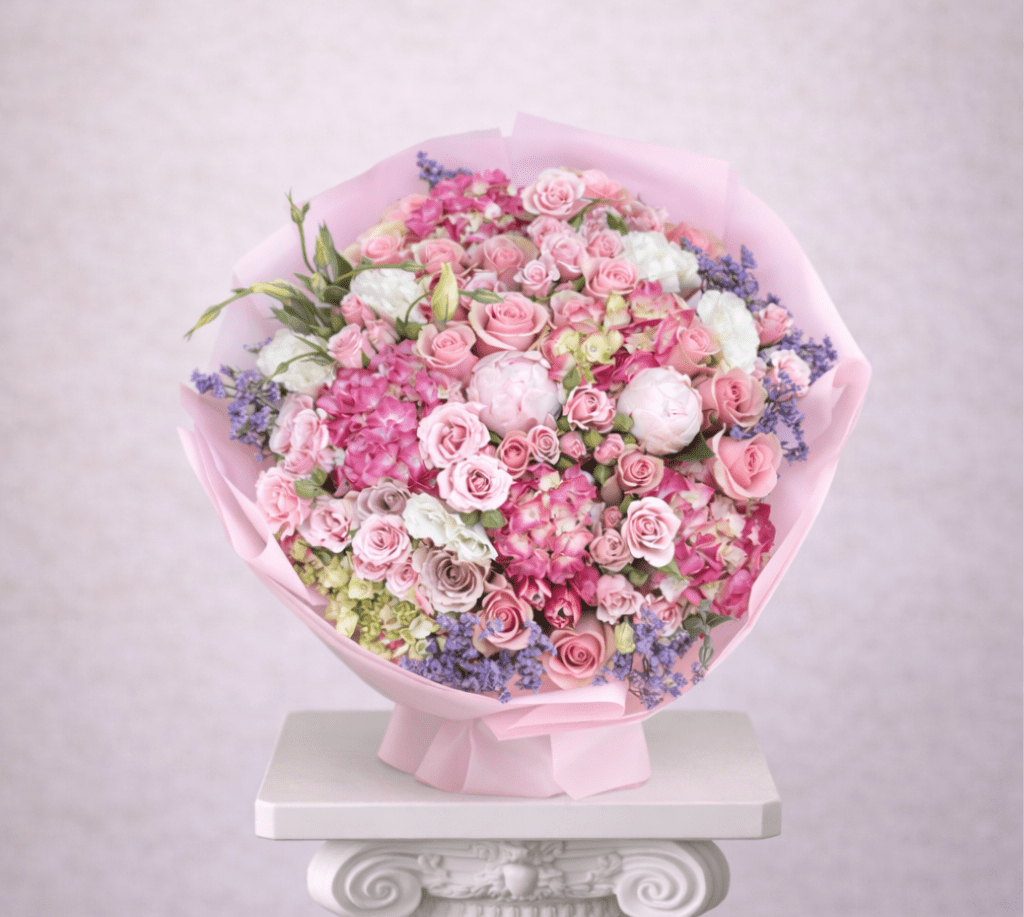 Large bouquet of pink roses and mixed blooms wrapped in pink paper