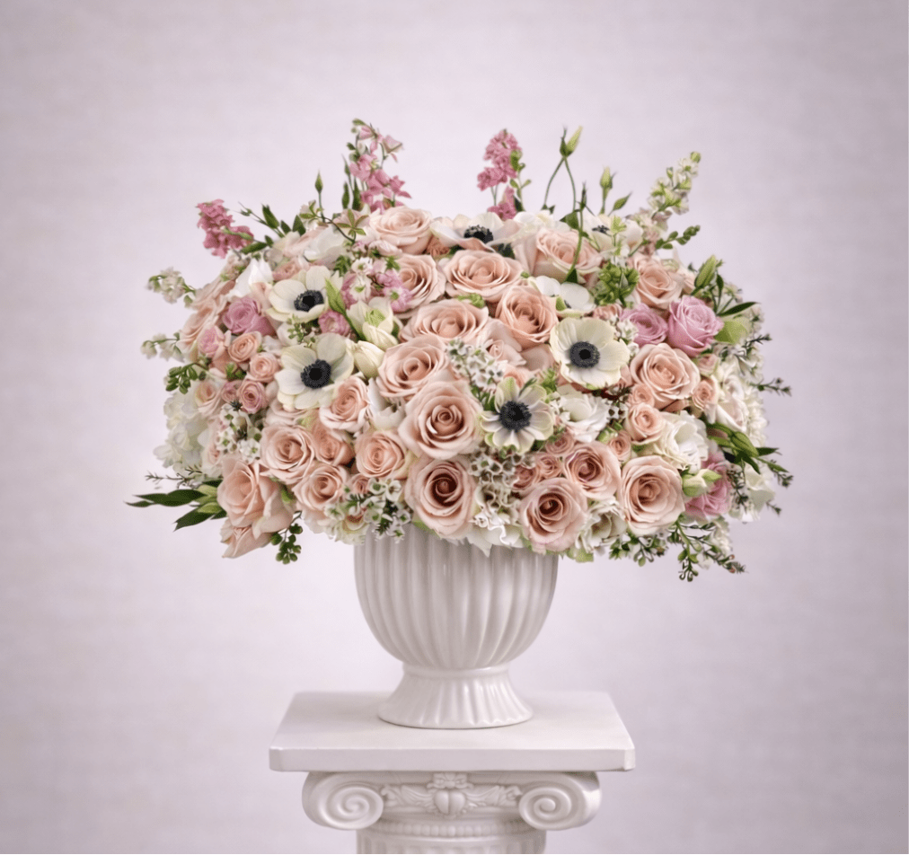 Blush and white rose arrangement in a white urn vase