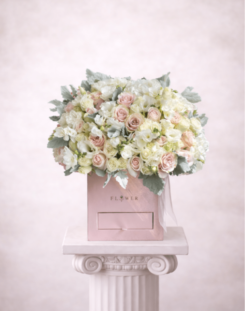 Pink and white rose bouquet in a pink box on a pedestal