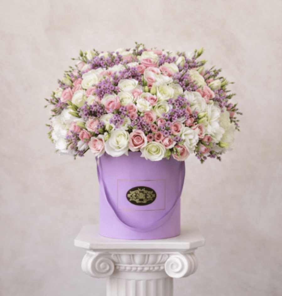 Pink and white roses with purple filler in a lavender hatbox