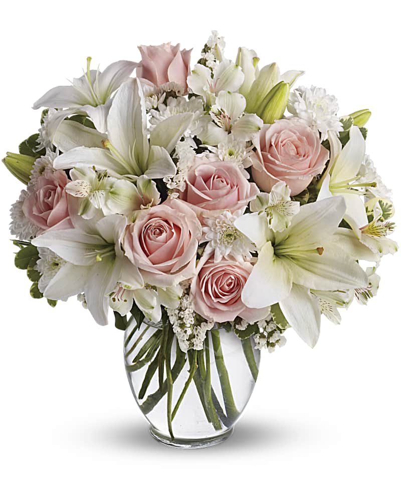 Pink roses and white lilies arranged in a clear glass vase