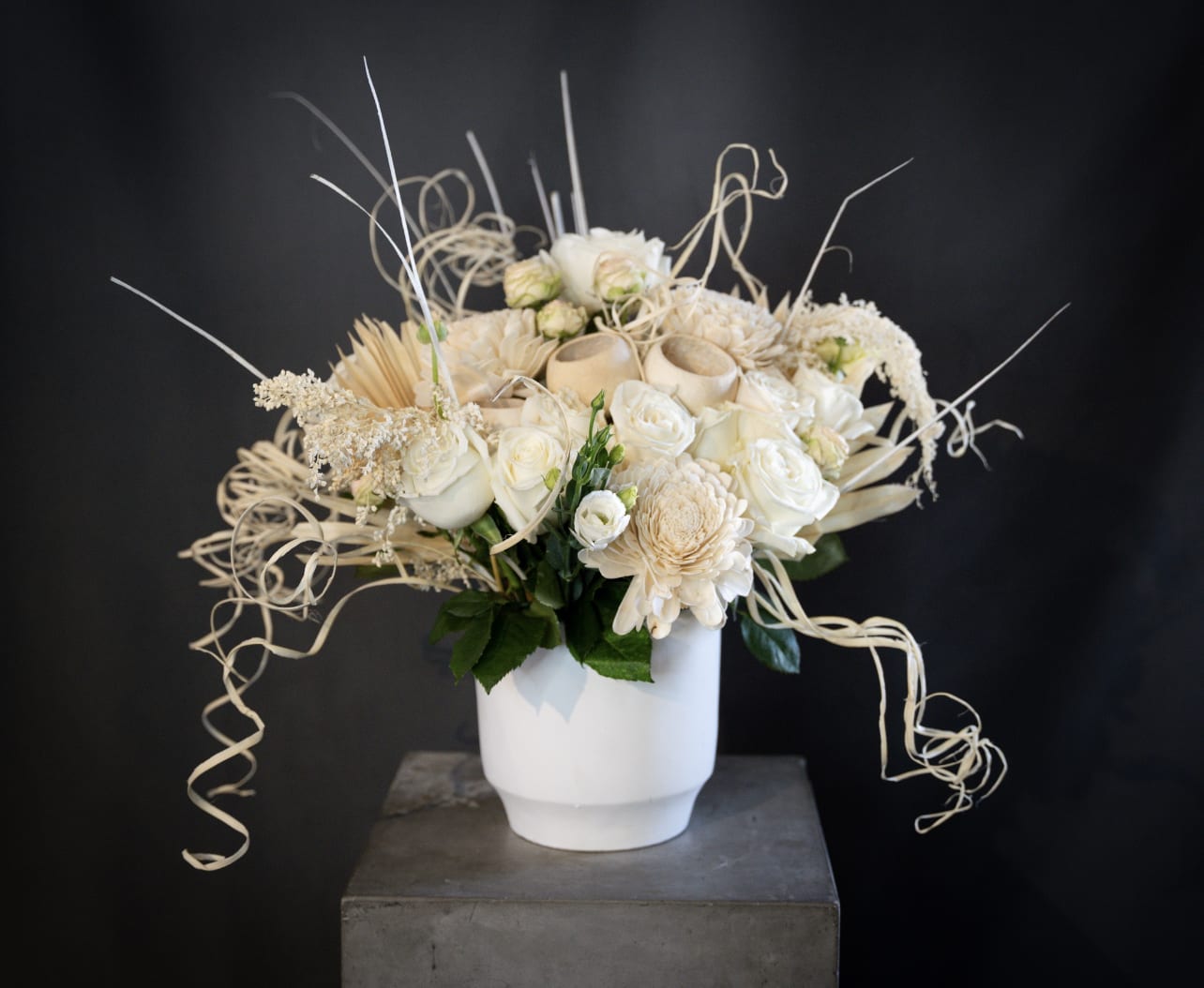 Cream floral arrangement in a white vase with curly decorative accents
