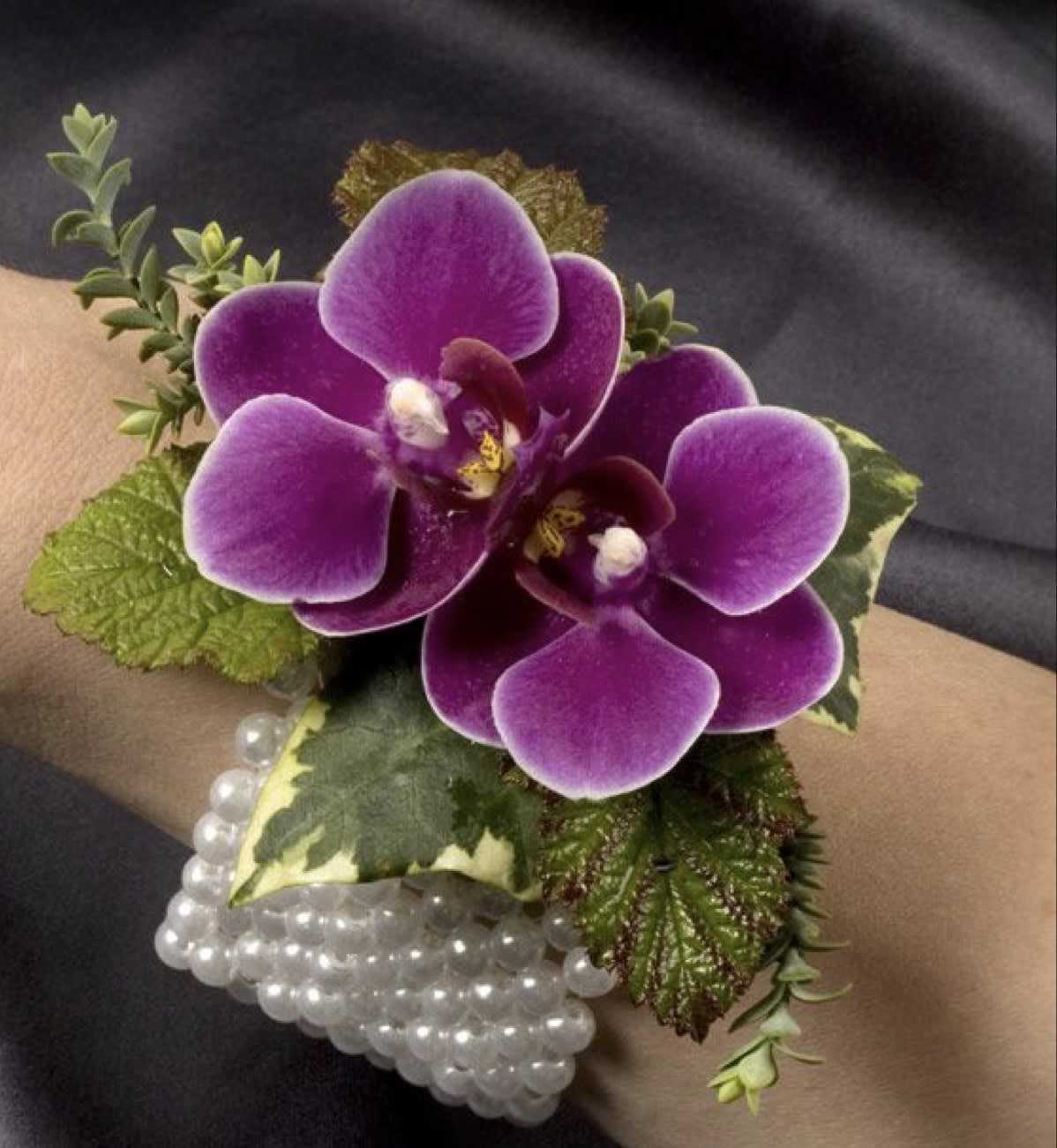 Purple orchid corsage with pearl bracelet on a wrist