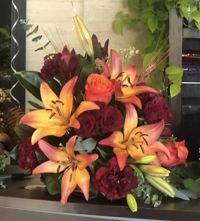 Lily &amp; Rose Cornucopia Centerpiece  - This cornucopia is overflowing with orange lilies and orange spray roses with red carnations hand-designed with lush fall leaves and foliage, making for a perfect centerpiece! **Only Large Size Left in Stock**