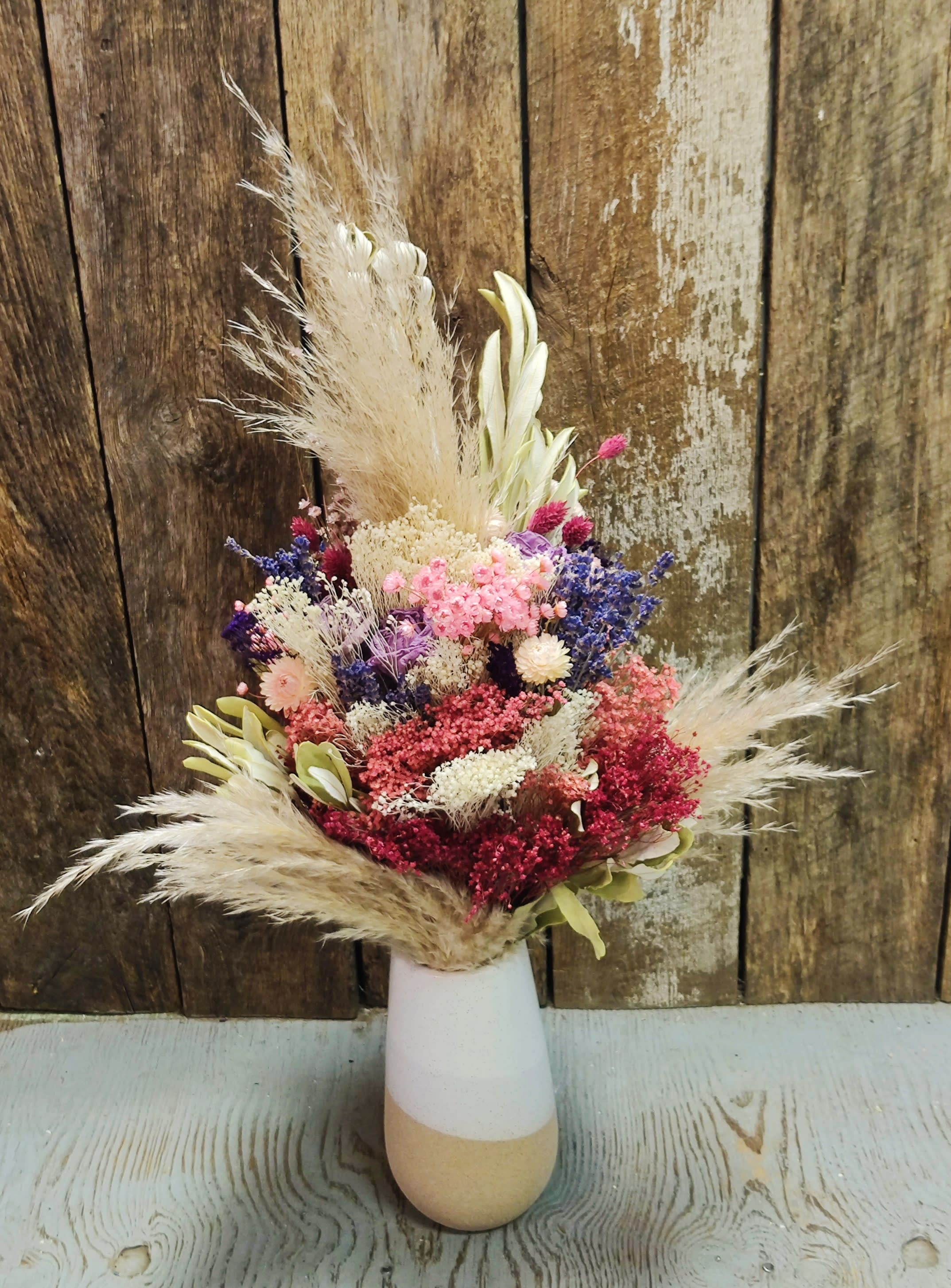 Dried flower arrangement in a white and tan vase
