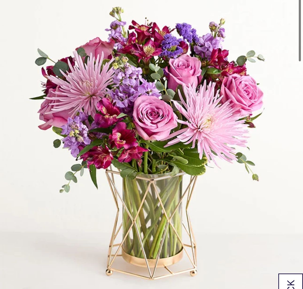 Pink and purple bouquet in a glass vase with a gold stand