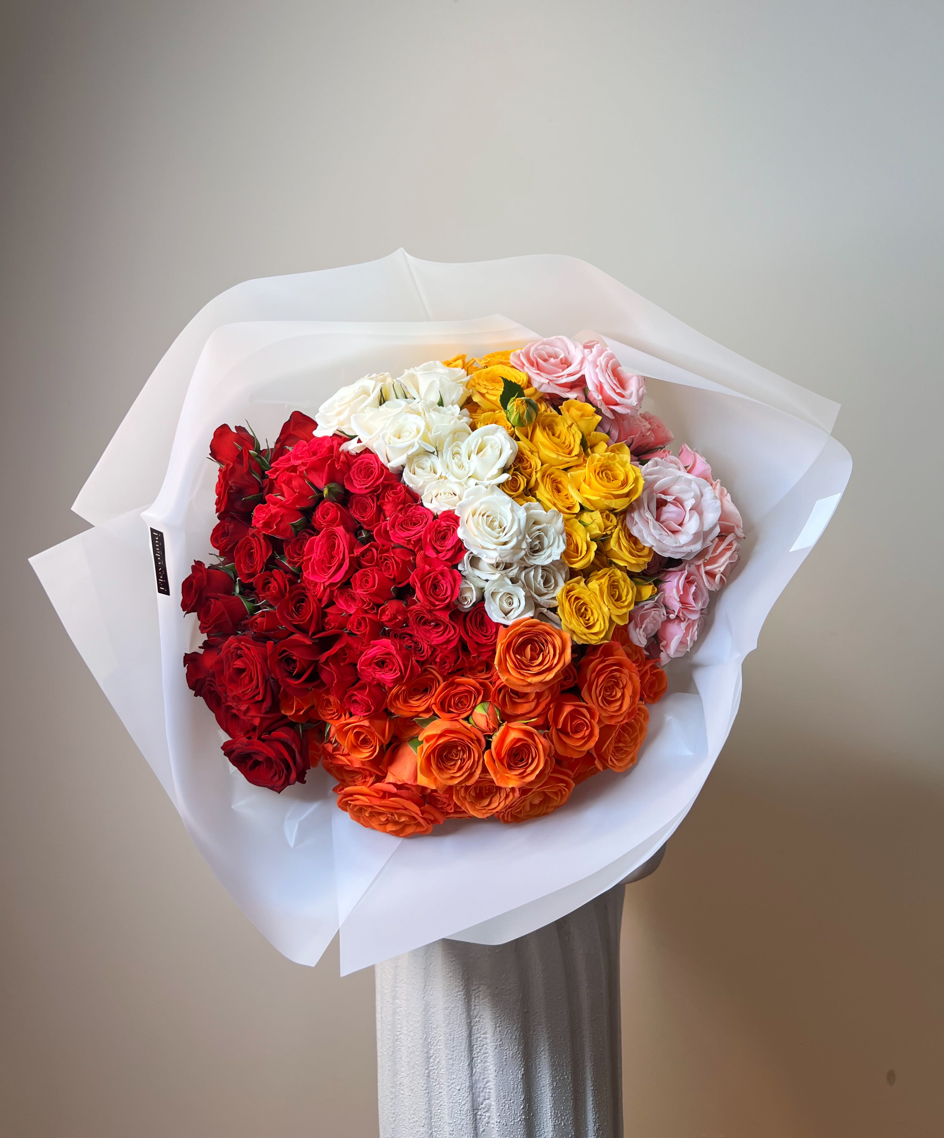 Large bouquet of multicolored roses wrapped in white paper