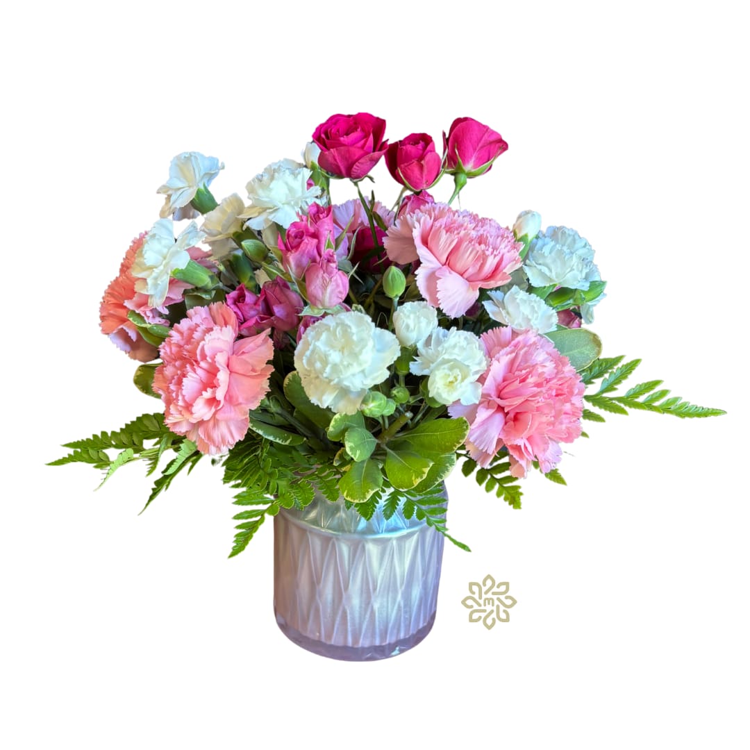 Blushing Bliss Bouquet - Indulge in the gentle elegance of our Blushing Bliss Bouquet, where classic beauty meets modern sophistication. This exquisite arrangement features an enchanting blend of white and pink mini carnations, full-sized carnations, and delicate pink spray roses.  The flowers are tastefully accented with a mix of lush greenery, creating a harmonious balance that is both refreshing and enchanting.  Housed in a stylish light pink glass decorative vase, this bouquet is perfect for adding a touch of charm to any room. Whether you're celebrating a special occasion or simply brightening someone's day, the Blushing Bliss Bouquet is sure to leave a lasting impression. 