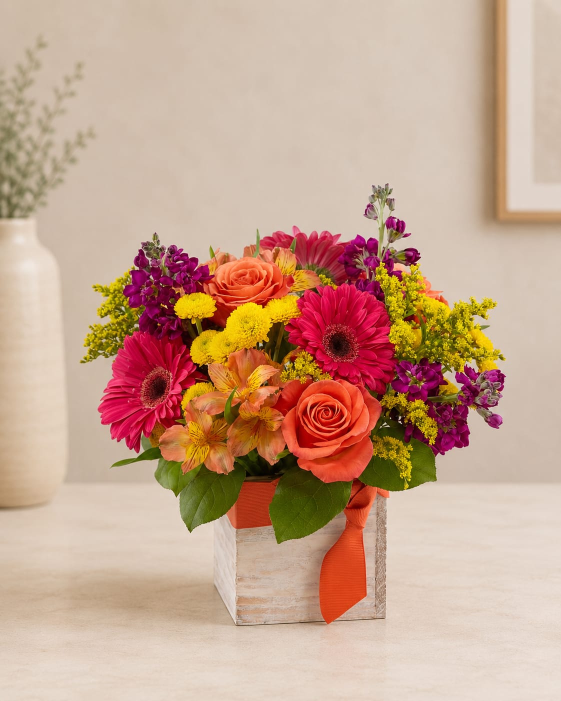 Bright mixed bouquet in a square wooden box with an orange ribbon