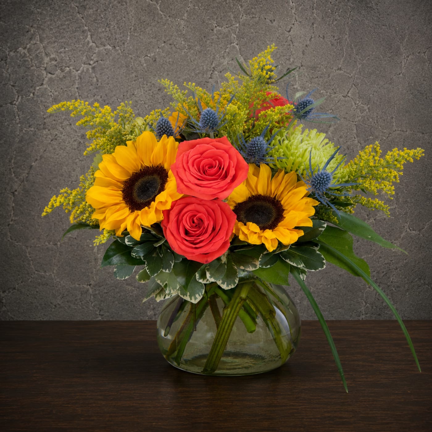 Bouquet of sunflowers and red roses in a glass vase