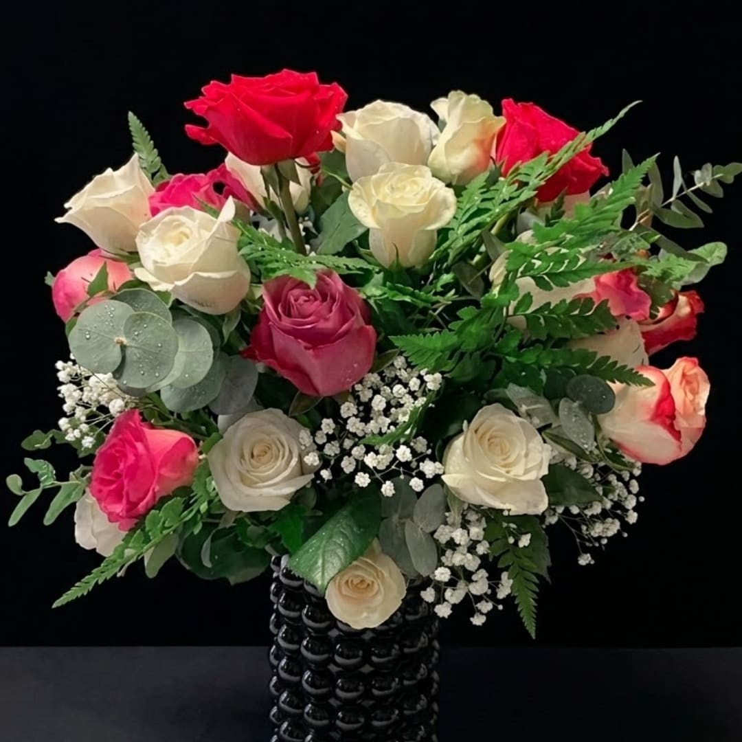 Bouquet of red, pink, and white roses in a black vase