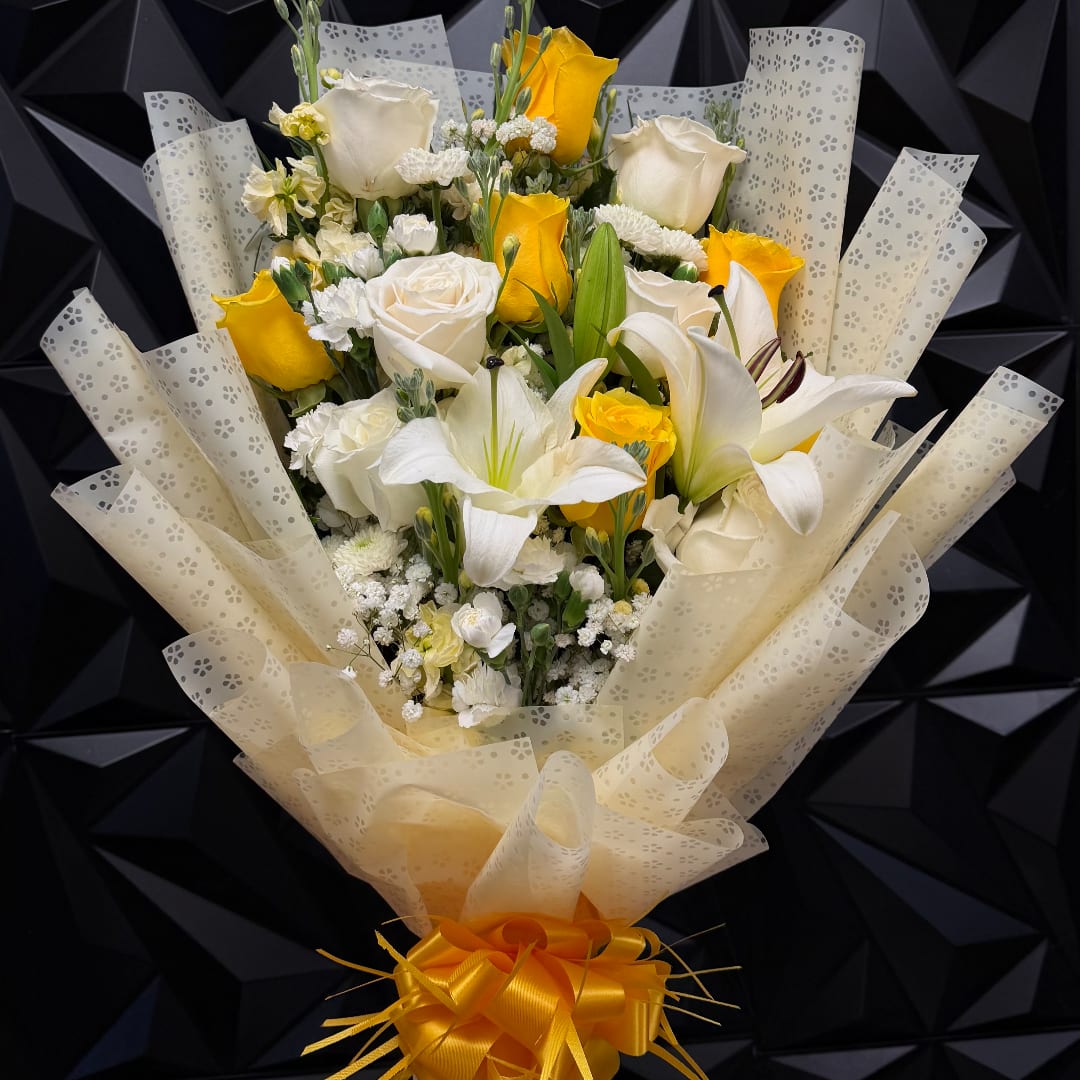 Bouquet of white and yellow roses with white lilies wrapped in patterned paper