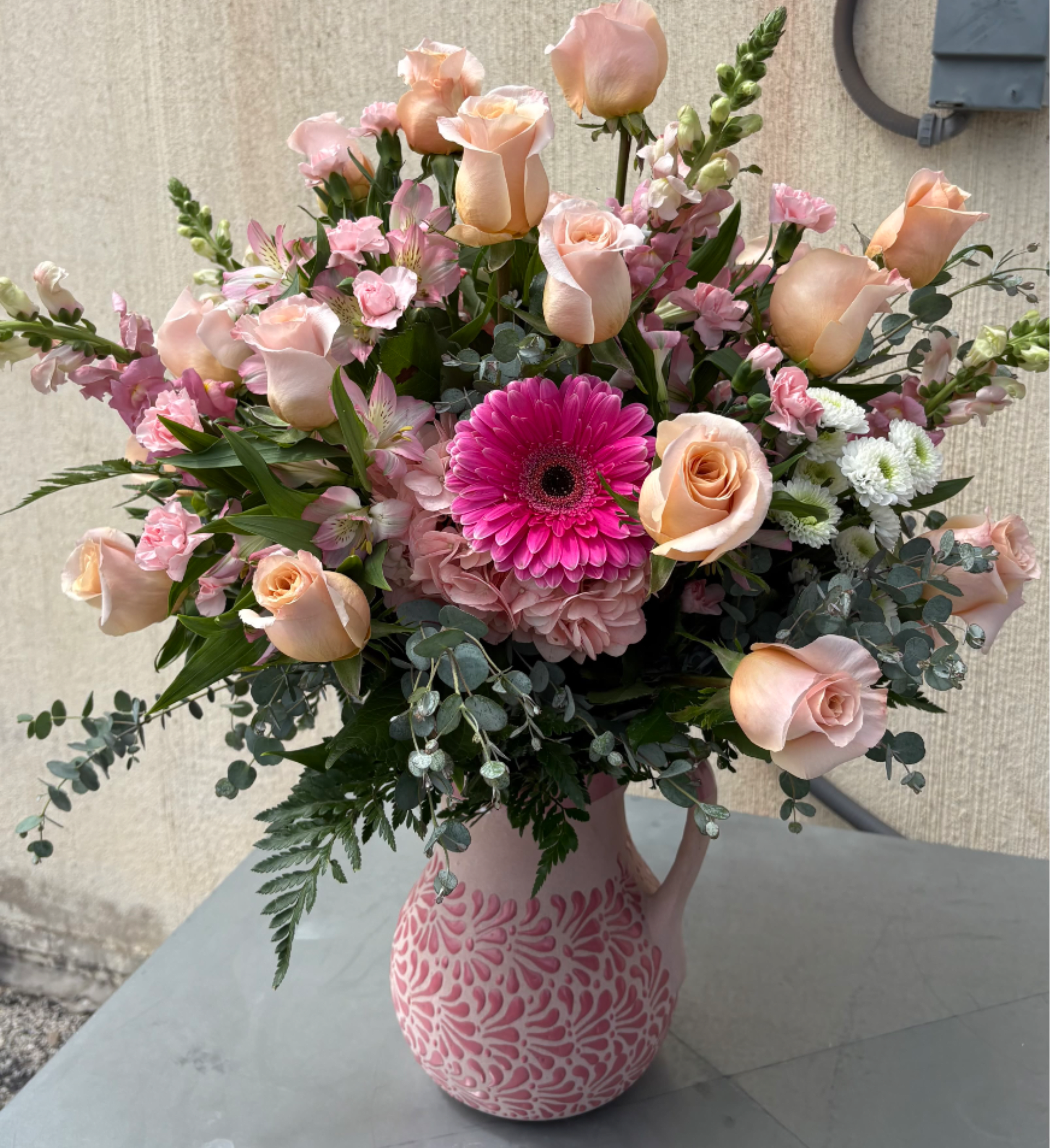 Pink and peach flower arrangement in a patterned vase