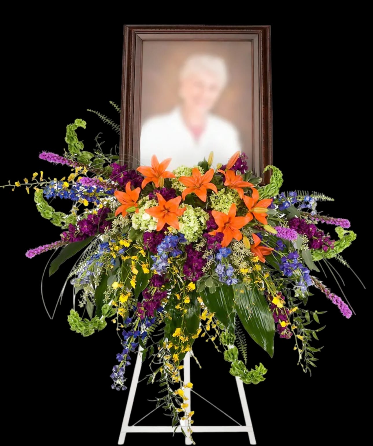 Standing floral spray with orange lilies and a framed portrait