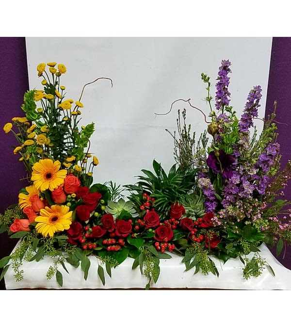 Large floral arrangement with red roses, yellow daisies, and purple spikes