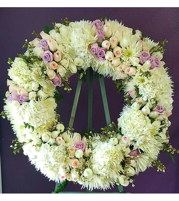 Large floral wreath of white and lavender blooms on a stand