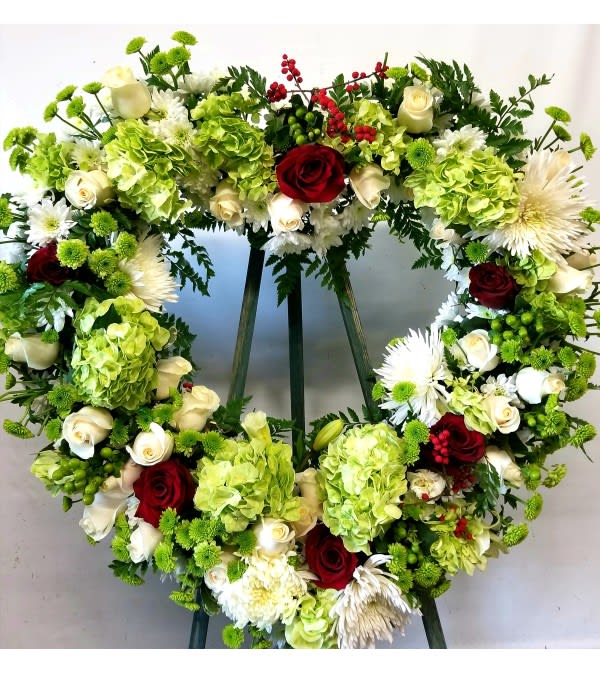 Heart-shaped floral wreath with red and white roses and green hydrangeas