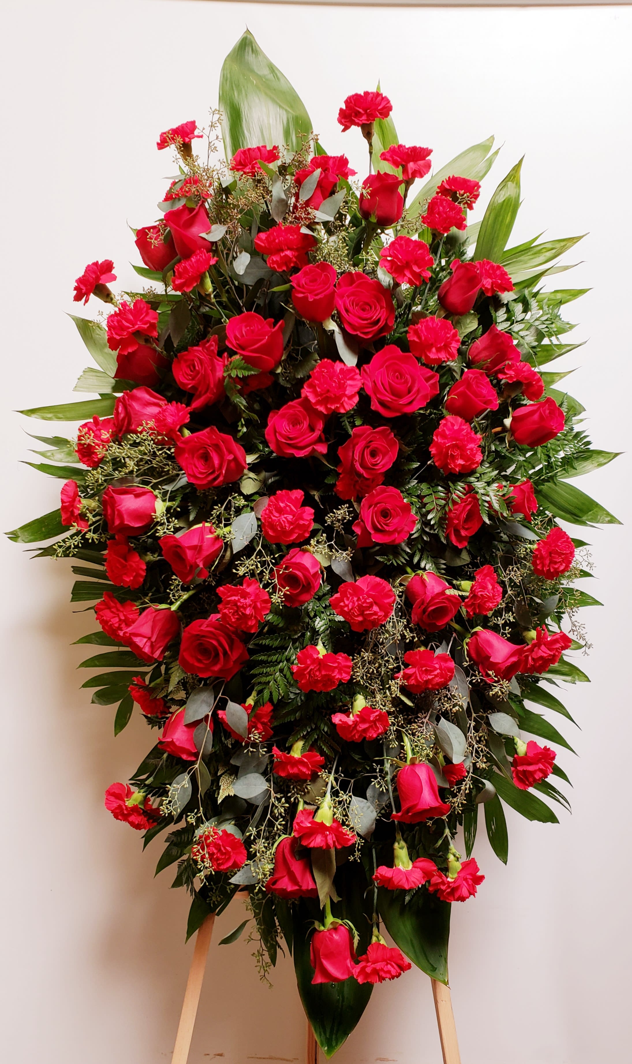 Large standing spray of red roses and carnations on an easel
