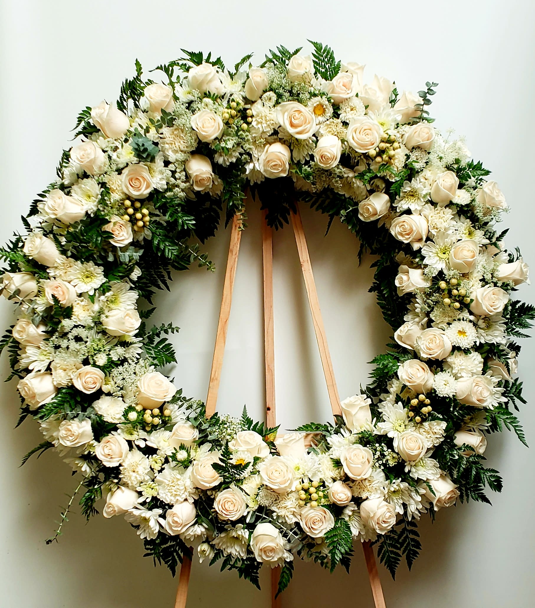 Large white floral wreath on a wooden easel