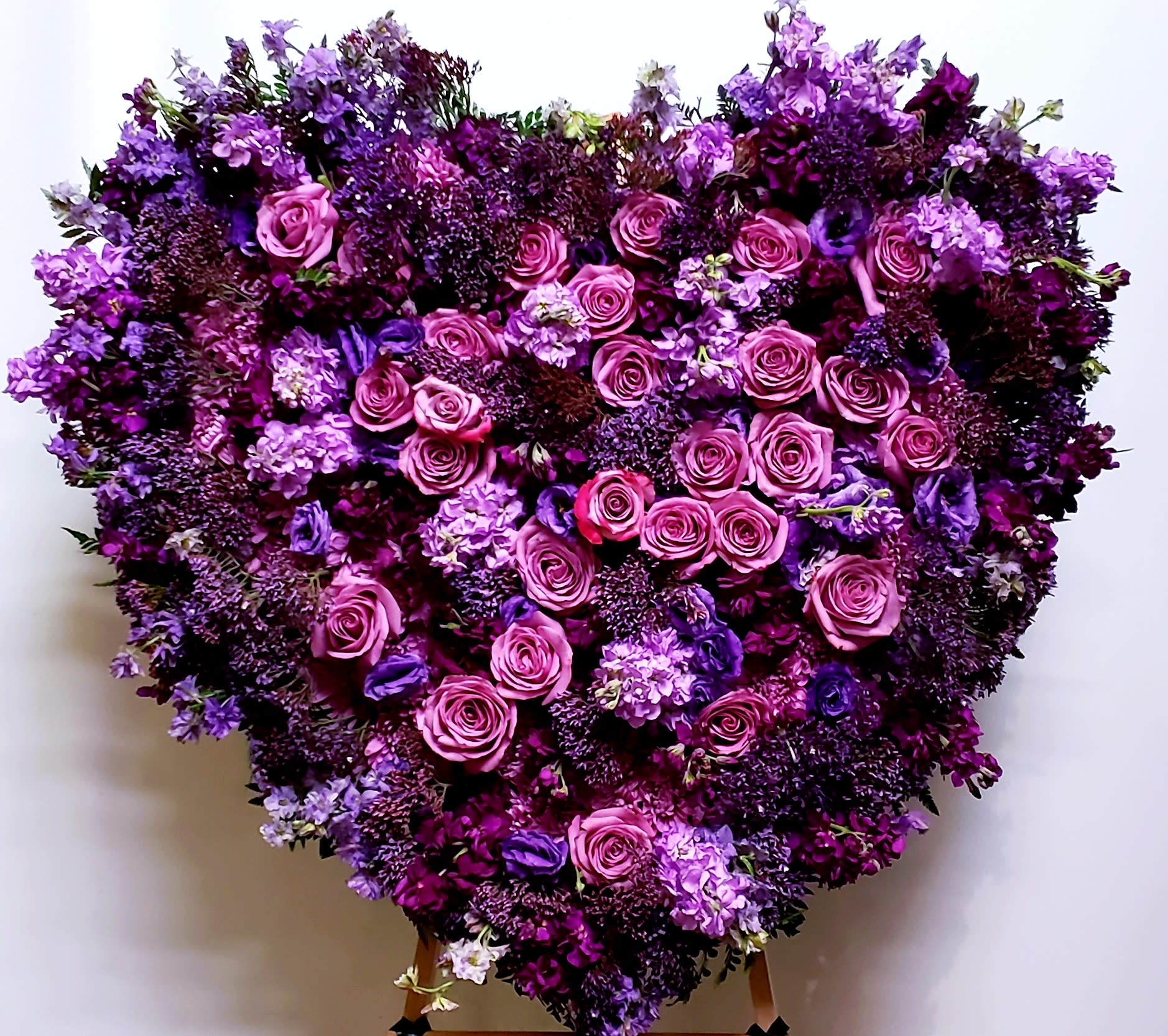 Heart-shaped floral arrangement of pink and purple roses