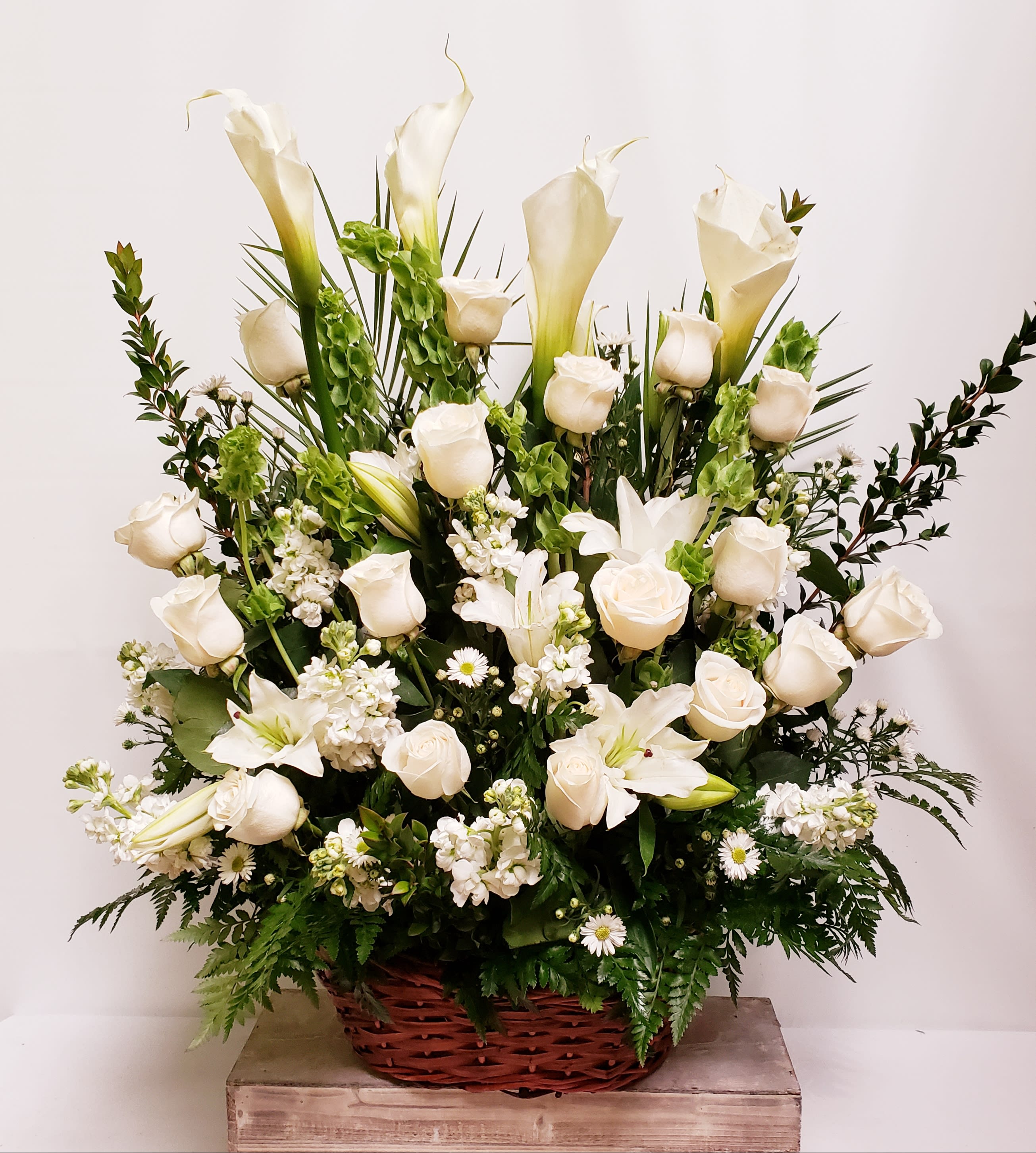 White roses and calla lilies in a wicker basket arrangement