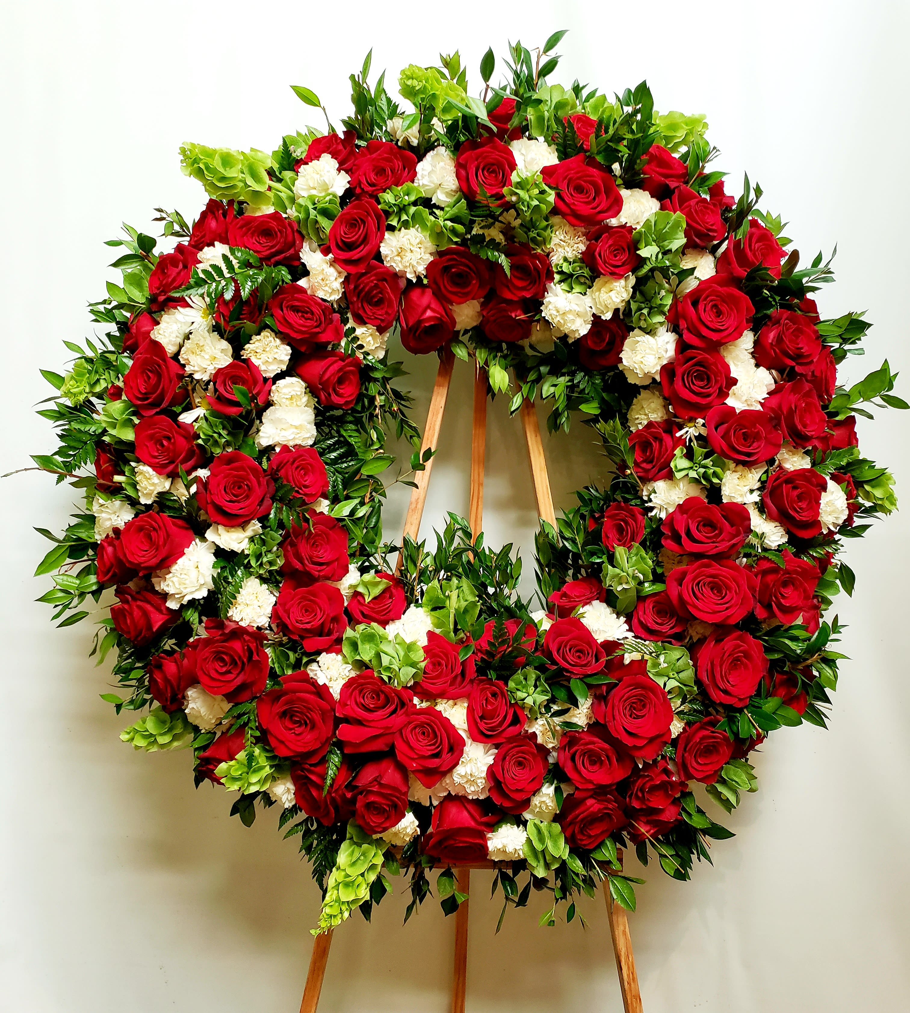 Large wreath of red roses and white carnations on a wooden easel