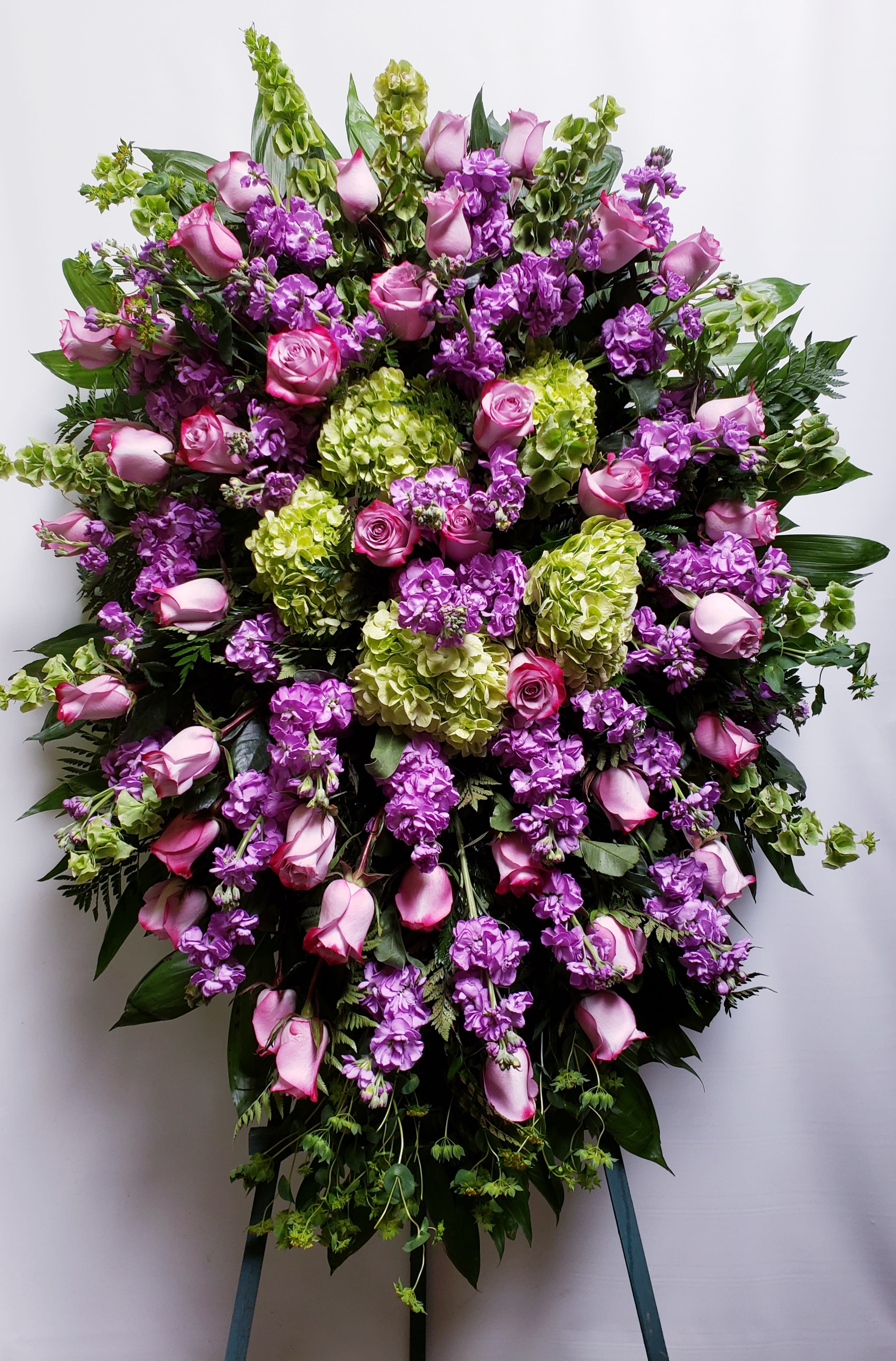 Large standing spray of pink roses, purple flowers, and green hydrangeas