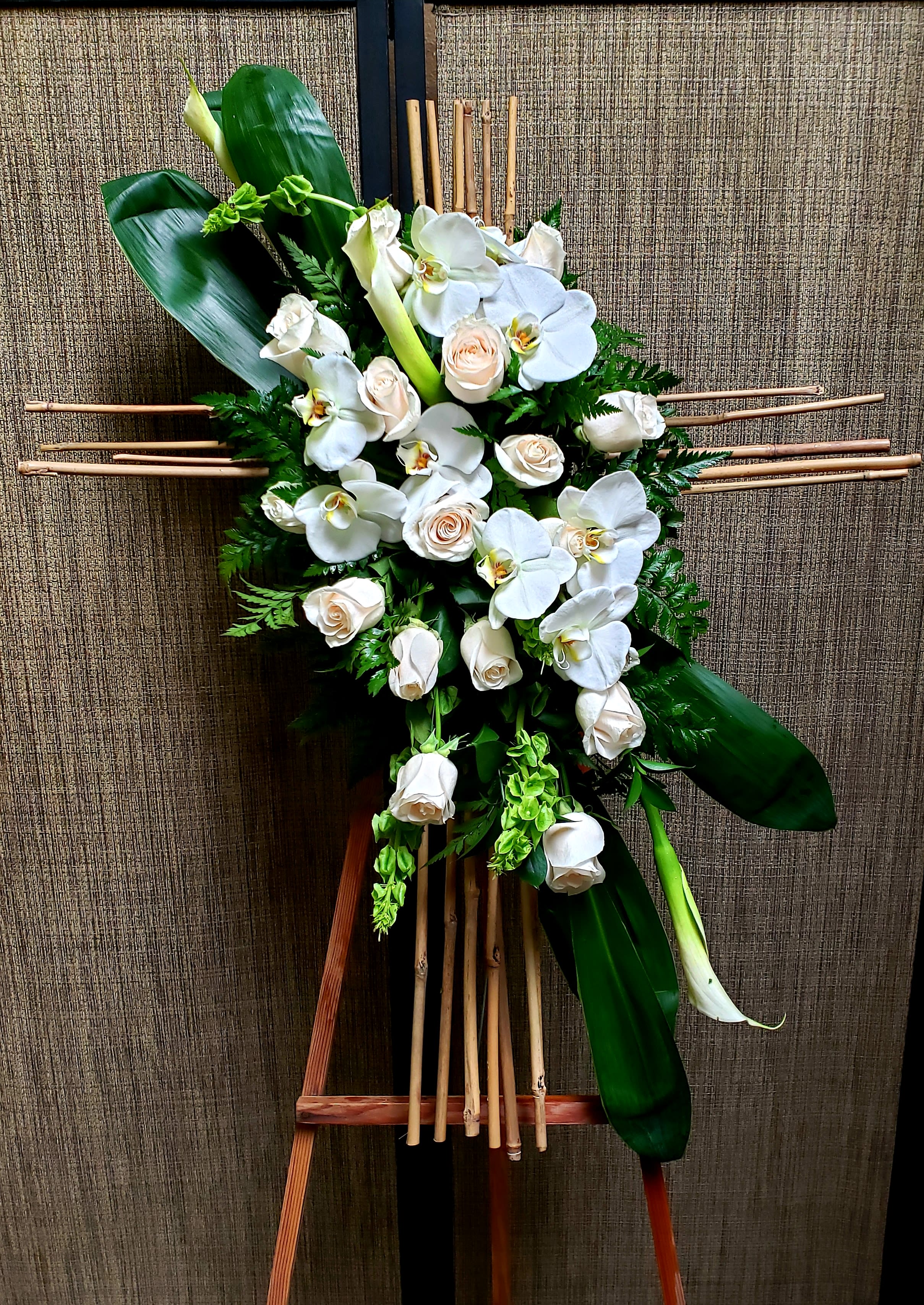 White orchids and roses arranged on a bamboo stand