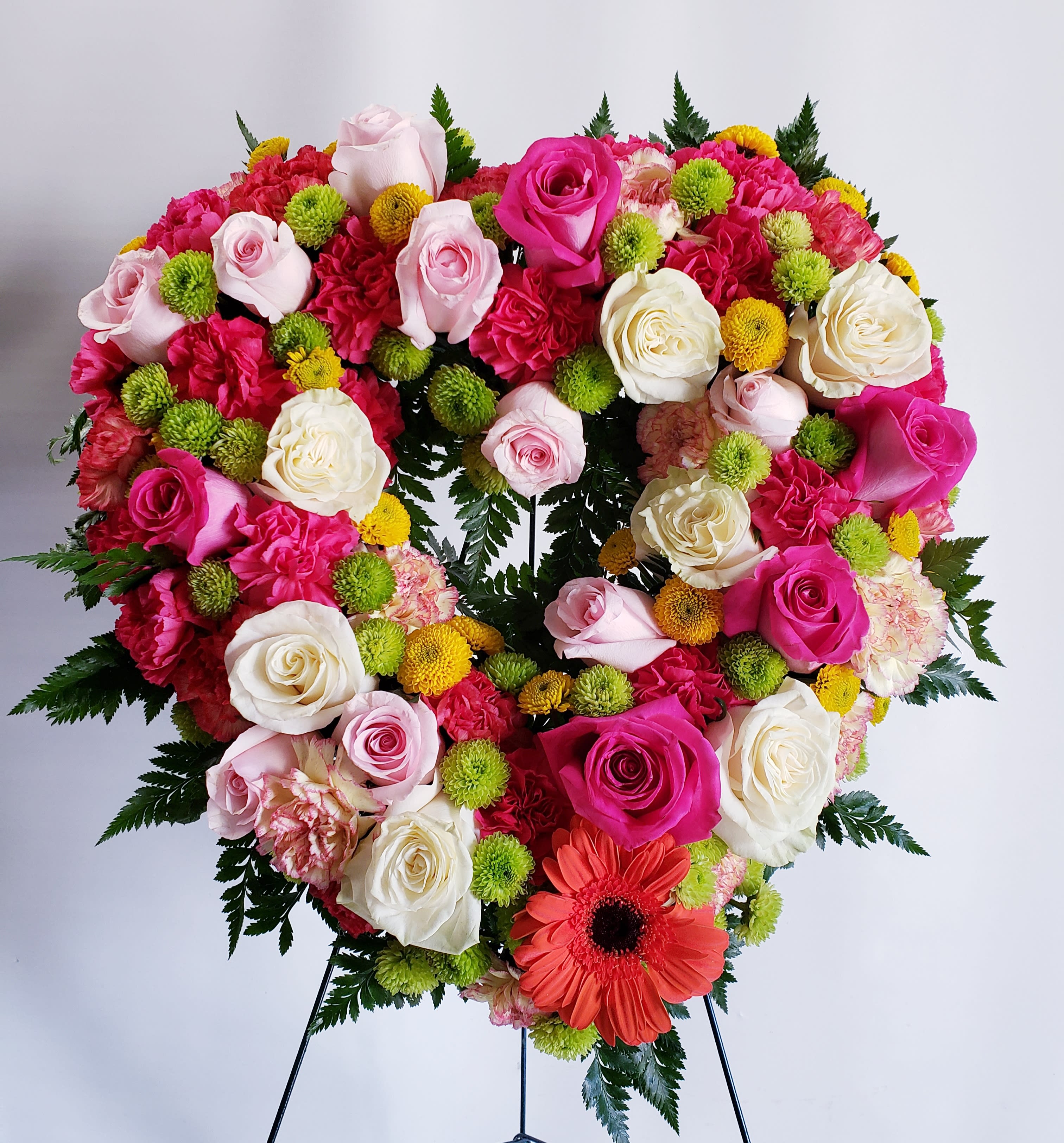Heart-shaped floral wreath with pink and white roses and bright accent flowers
