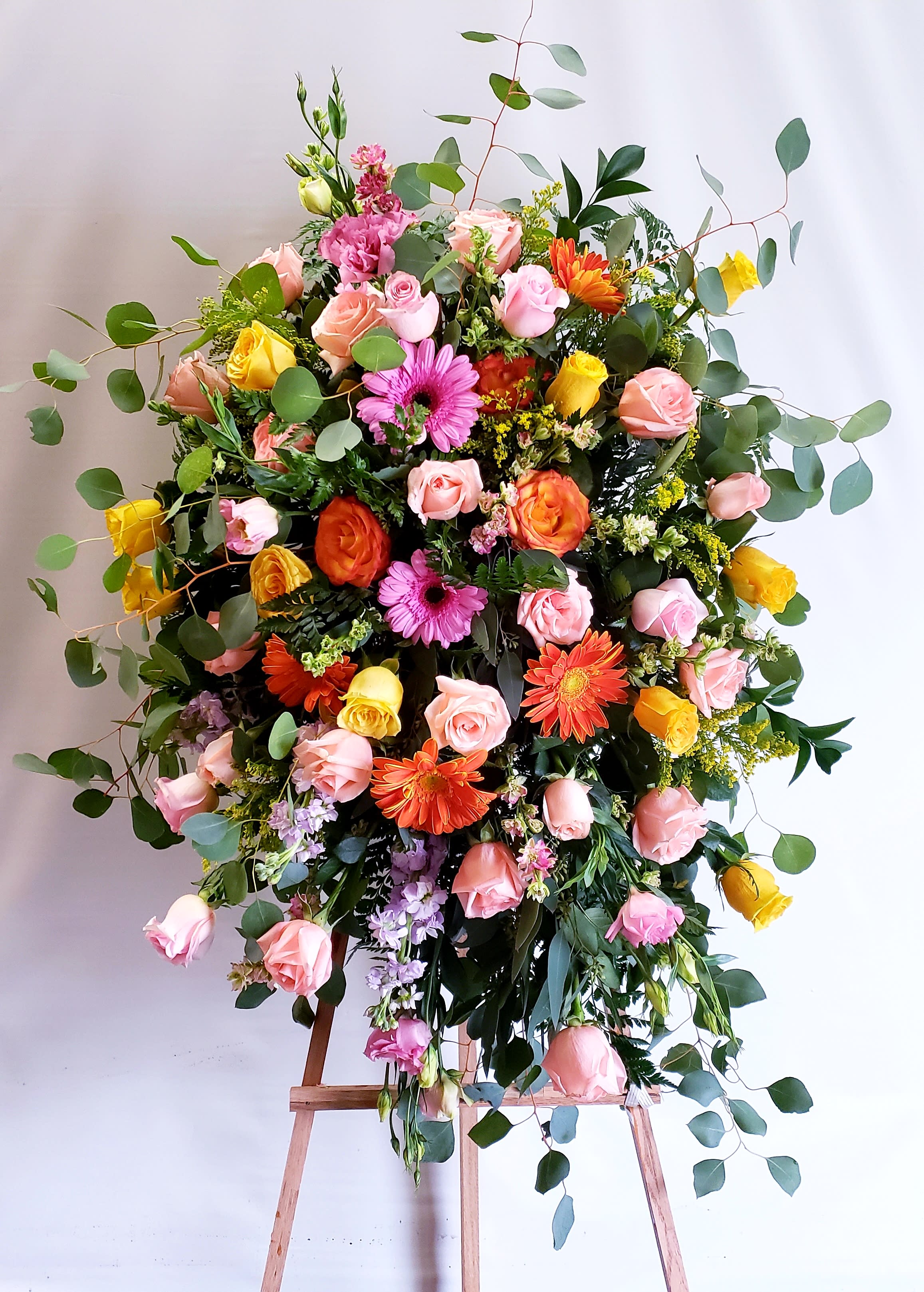 Large mixed flower arrangement on an easel with pink, yellow, and orange blooms